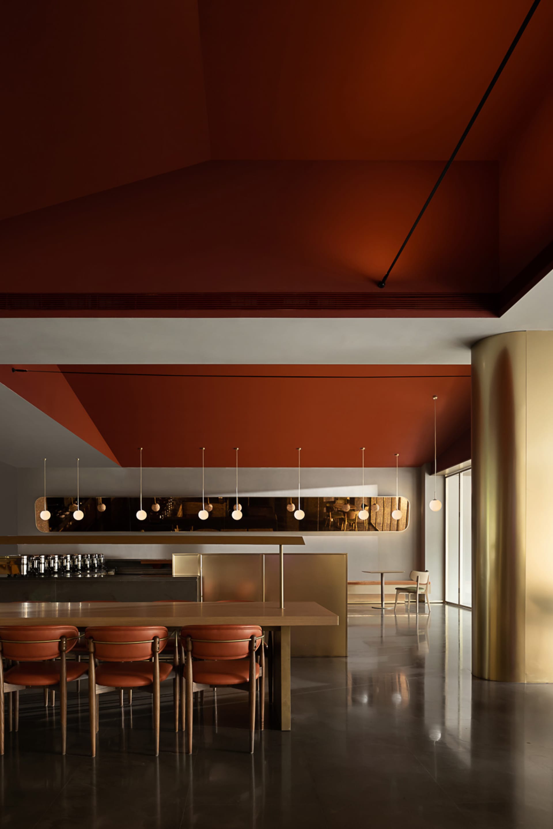 A modern restaurant interior with a terracotta ceiling and a gold pillar, showcasing contemporary design elements.