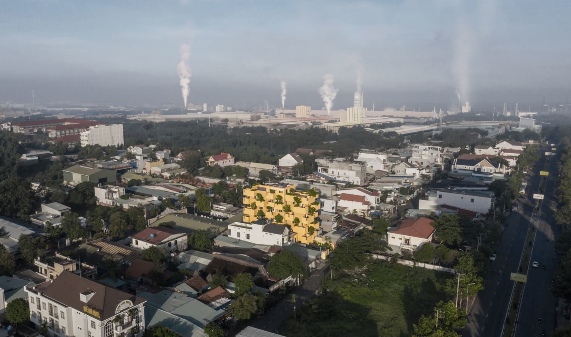 Aerial view of a cityscape with industrial areas in the background and residential and commercial buildings in the foreground