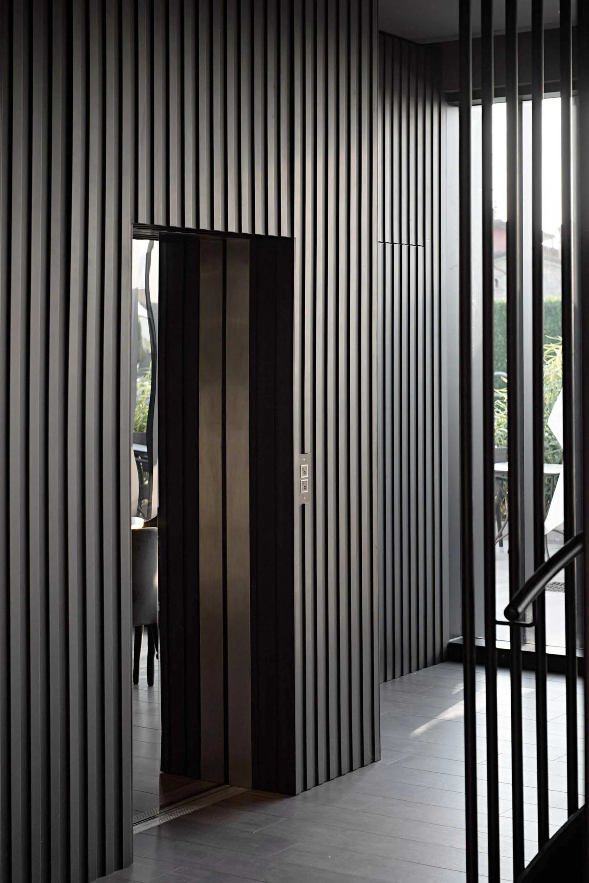 A modern elevator interior with metallic panels and a glass door.