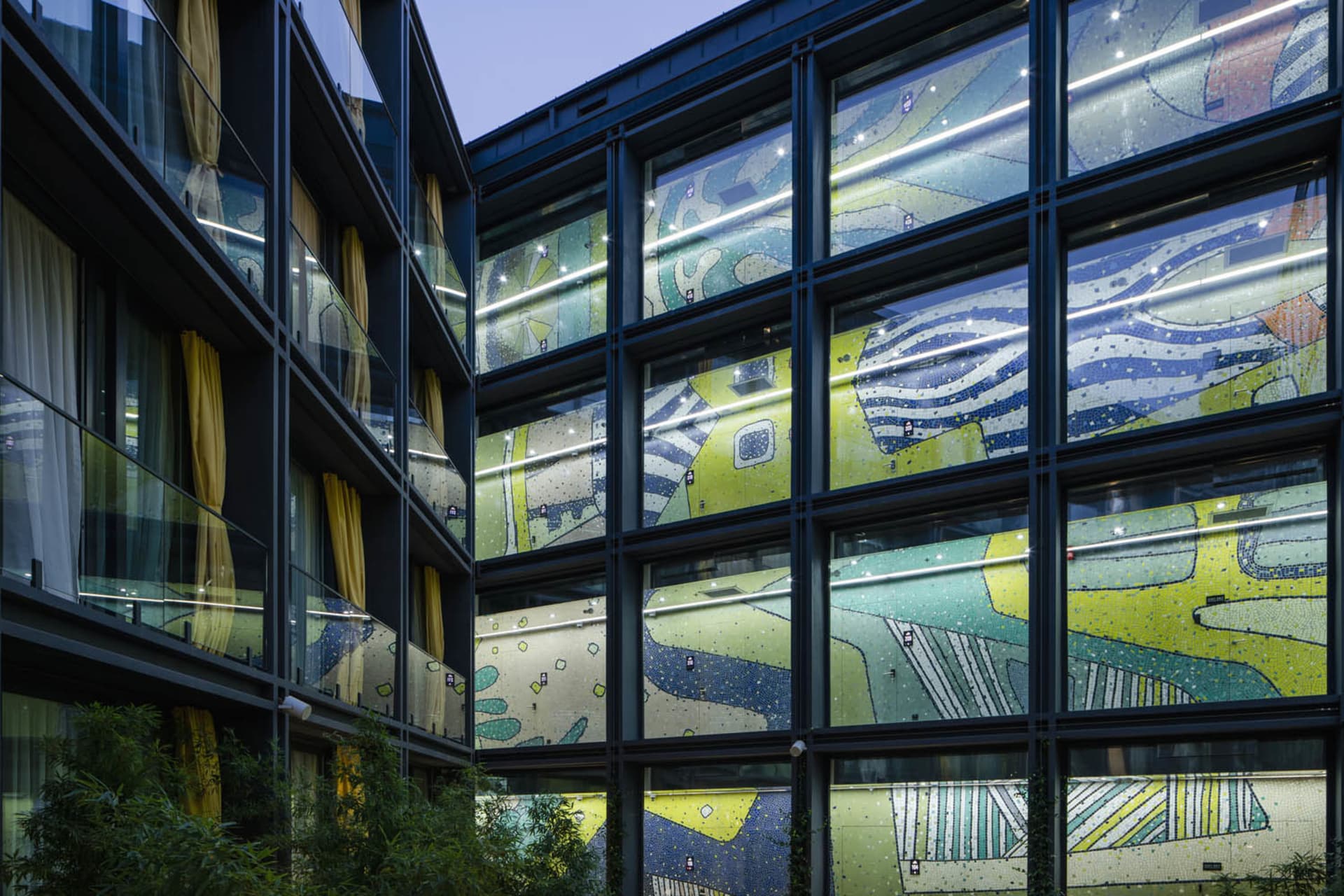 A modern commercial building features intricate glass mosaics on its facade.