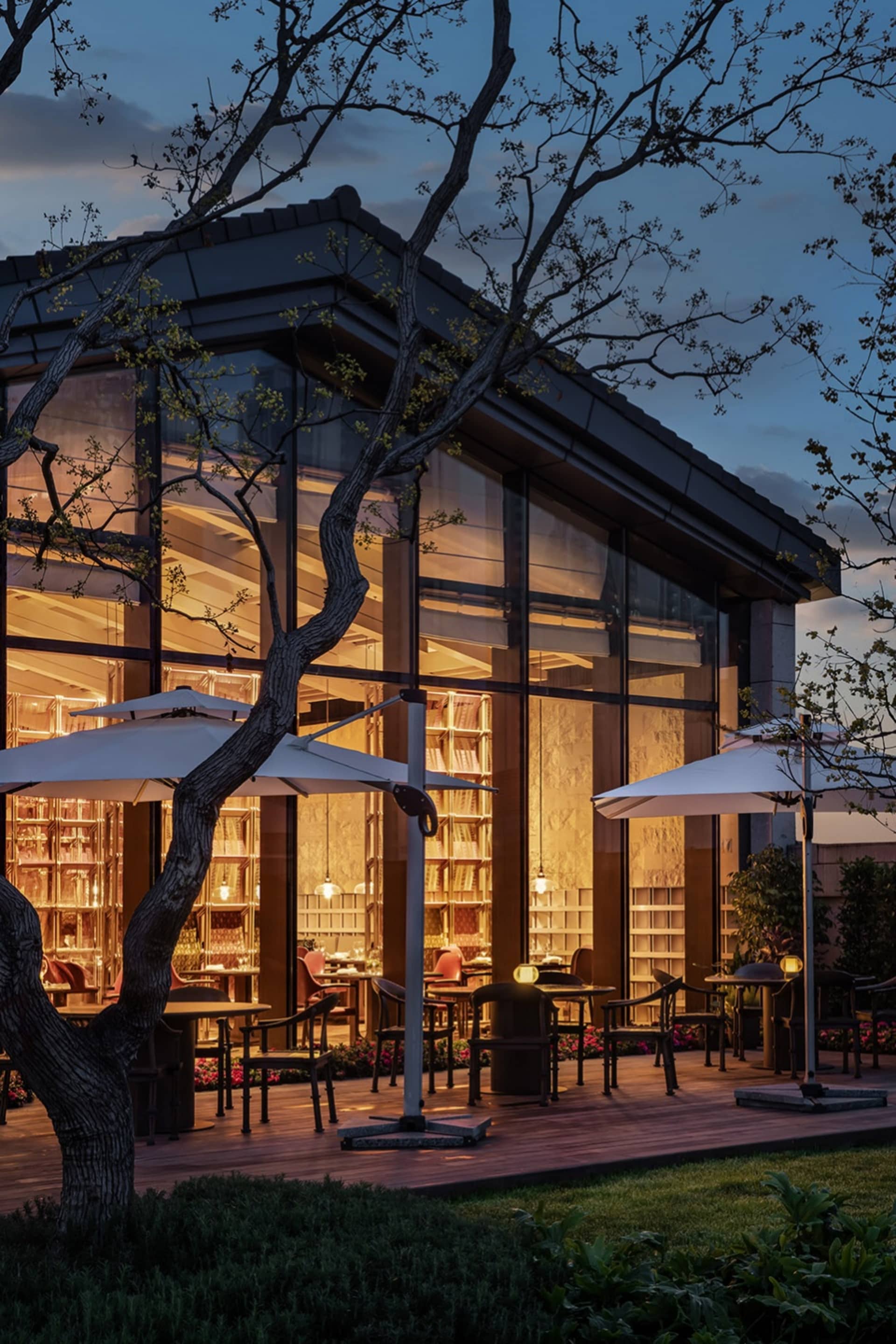 Modern restaurant exterior with glass walls at dusk