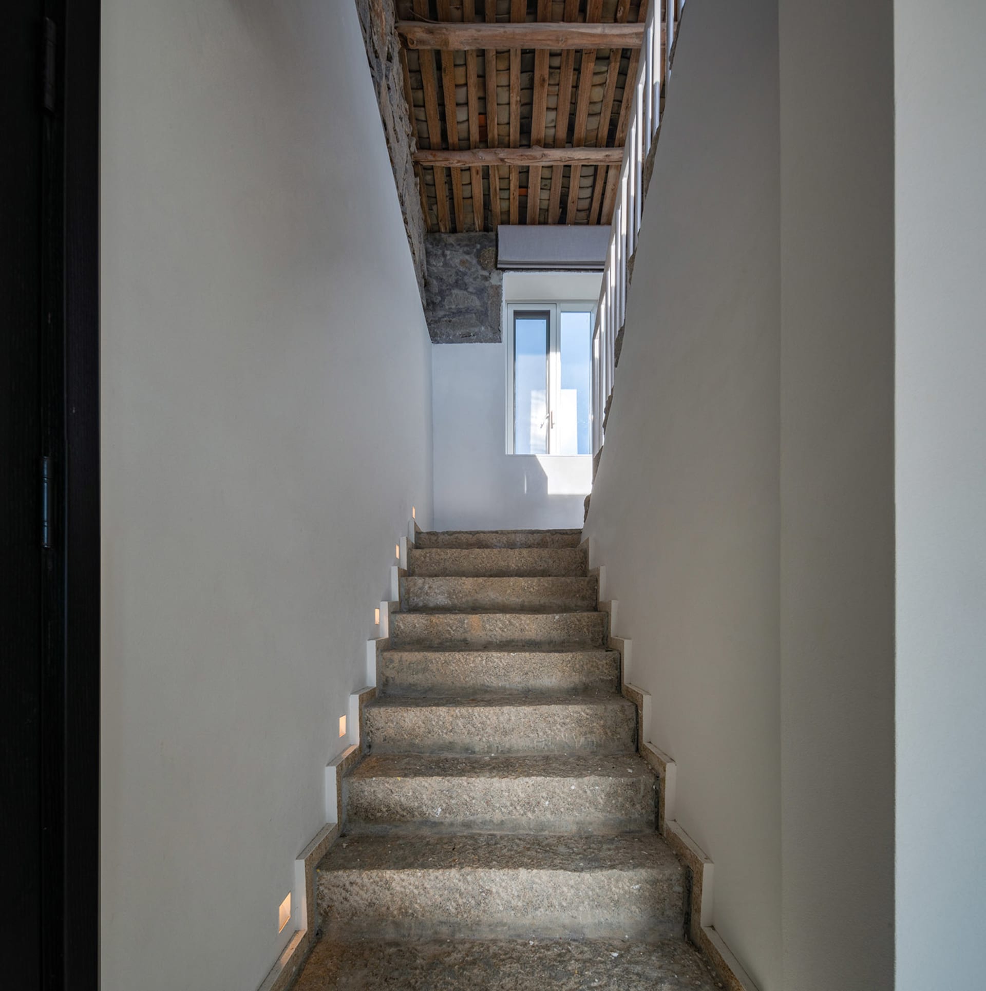 Concrete staircase with walls and wooden beams in an industrial design setting.