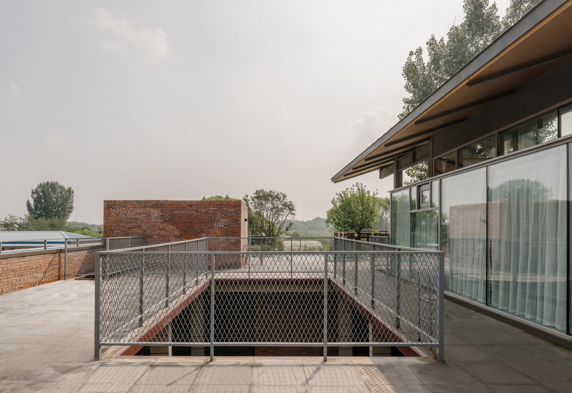 A modern metal roof deck with a brick building in the background and a flat roof with a clear sky.