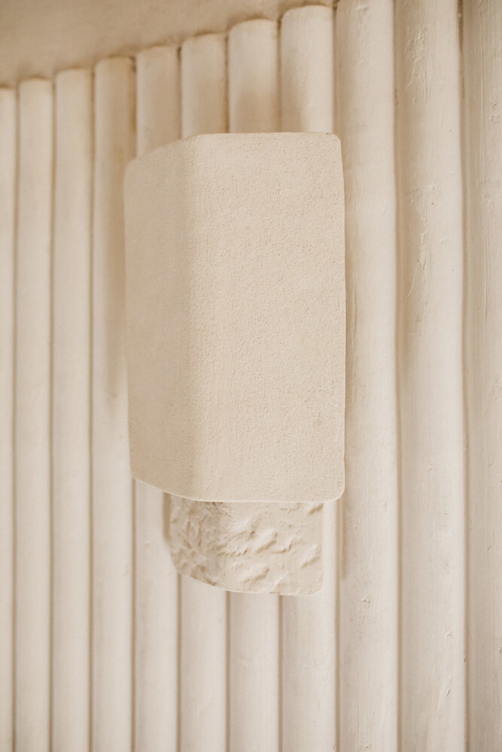 A minimalist architectural concrete detail hanging on a vertical column structure.