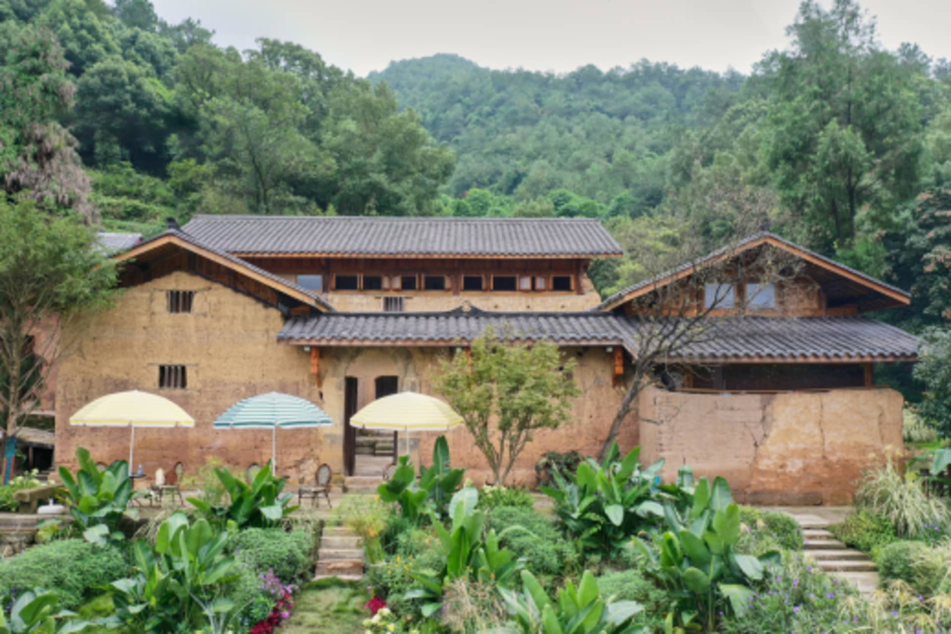 陶土覆面的房屋搭配赤陶瓦屋頂與木質點綴，坐落於丘陵景觀之中。