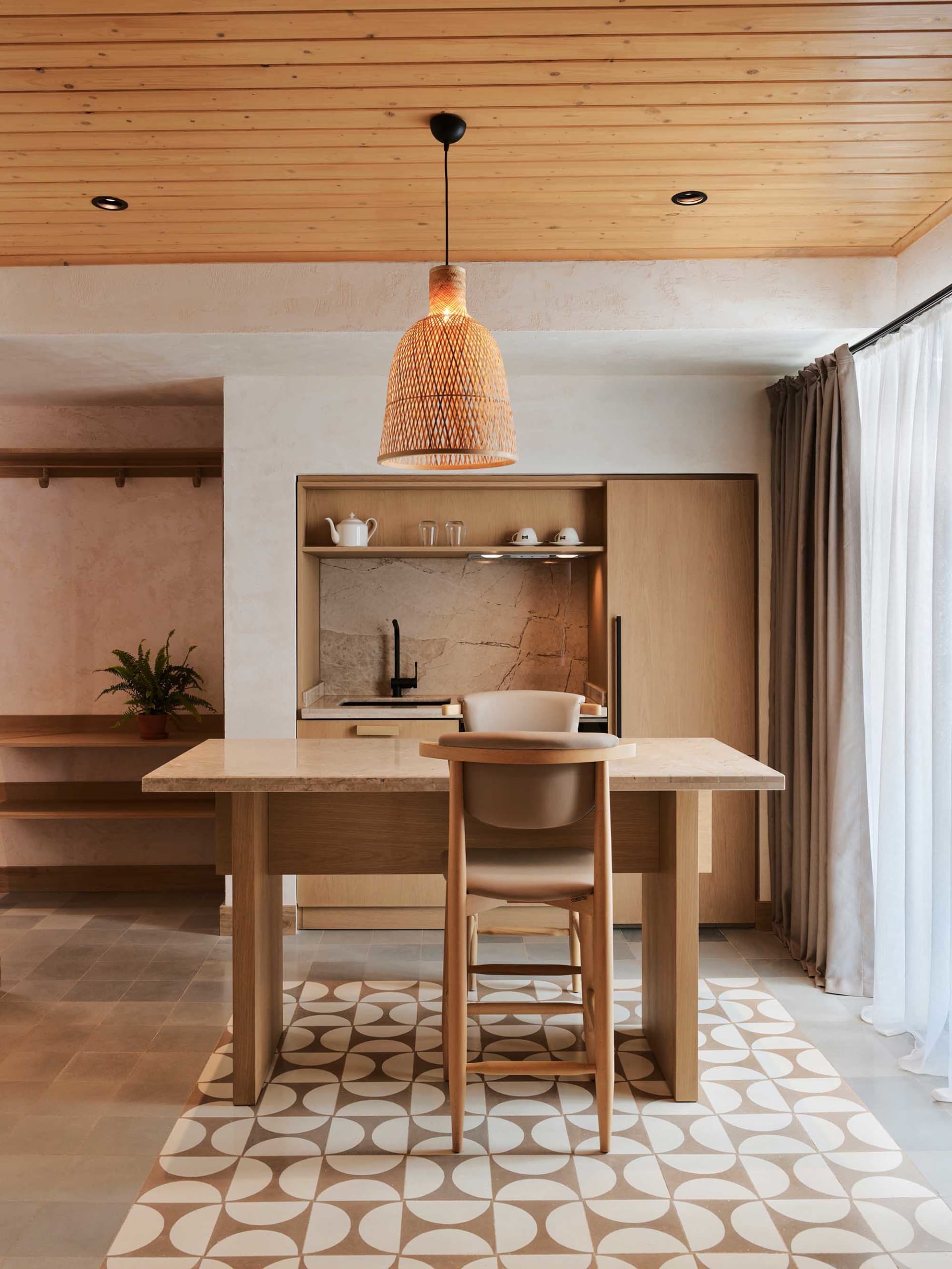 Modern kitchen with wooden countertop and marble backsplash, featuring a pendant light with a woven texture