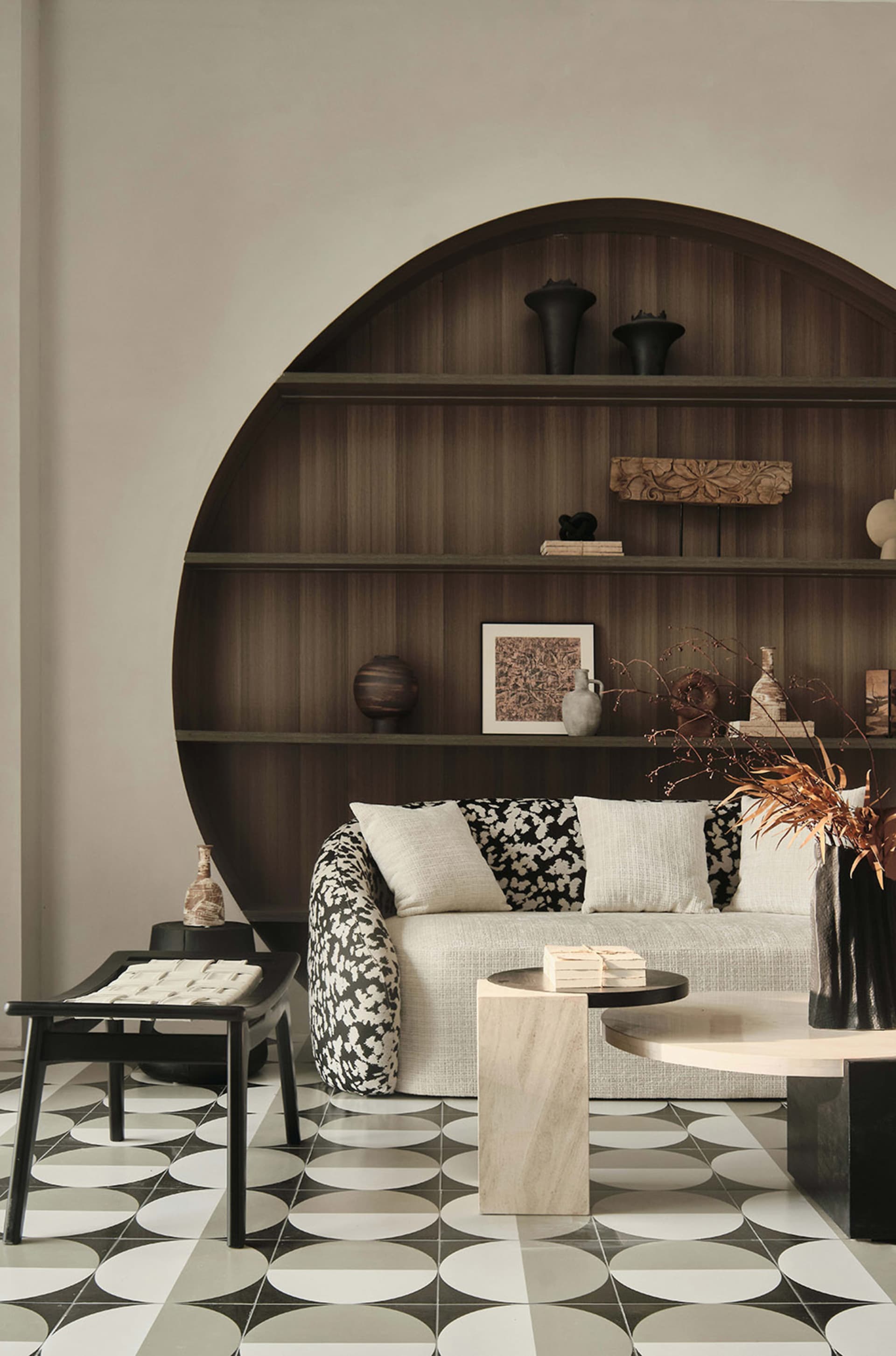 Modern living room with a round wooden shelf, a white sofa with black and white floral upholstery, and marble and concrete fu