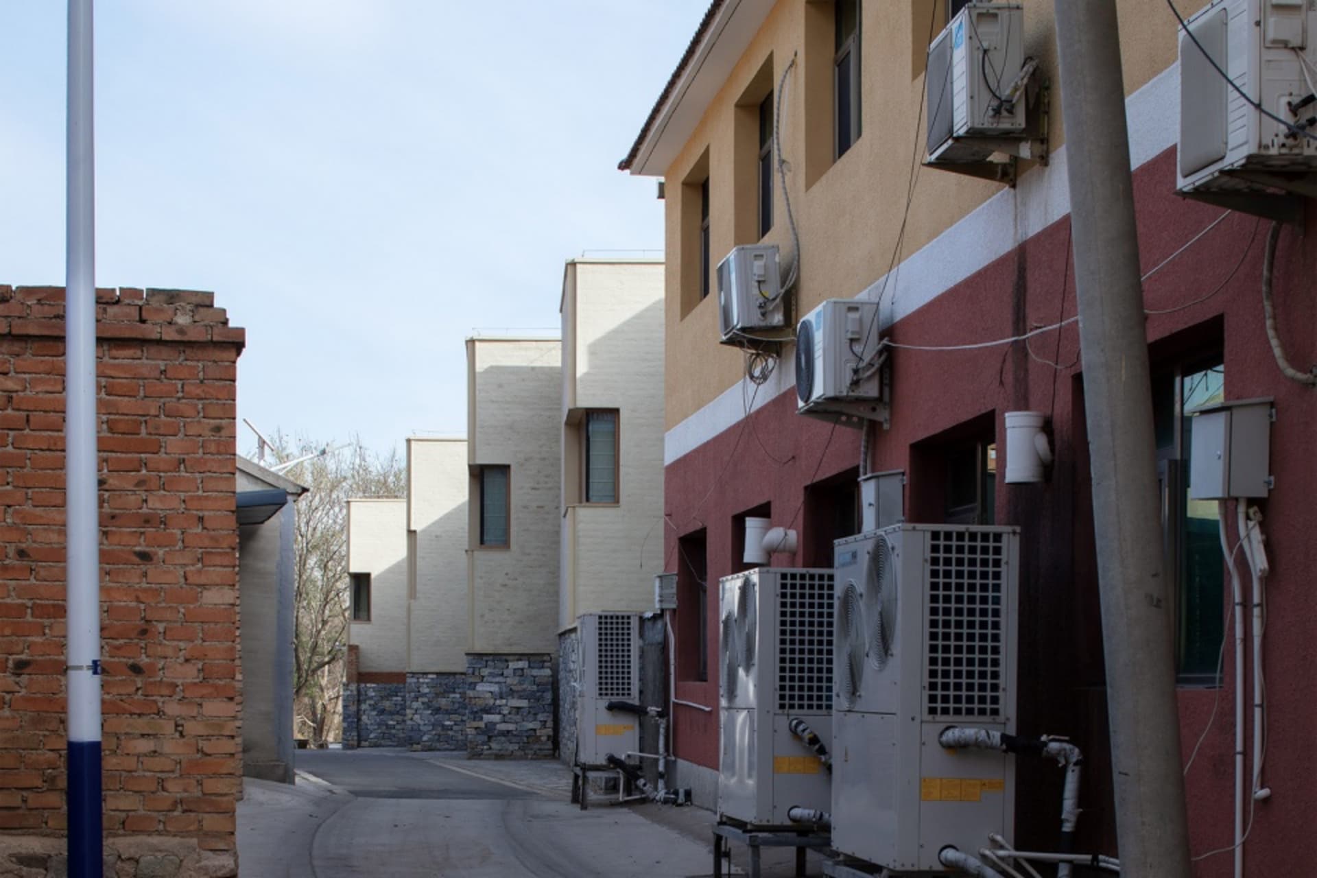 A city street with buildings incorporating concrete exteriors and airconditioning units attached to the facade.