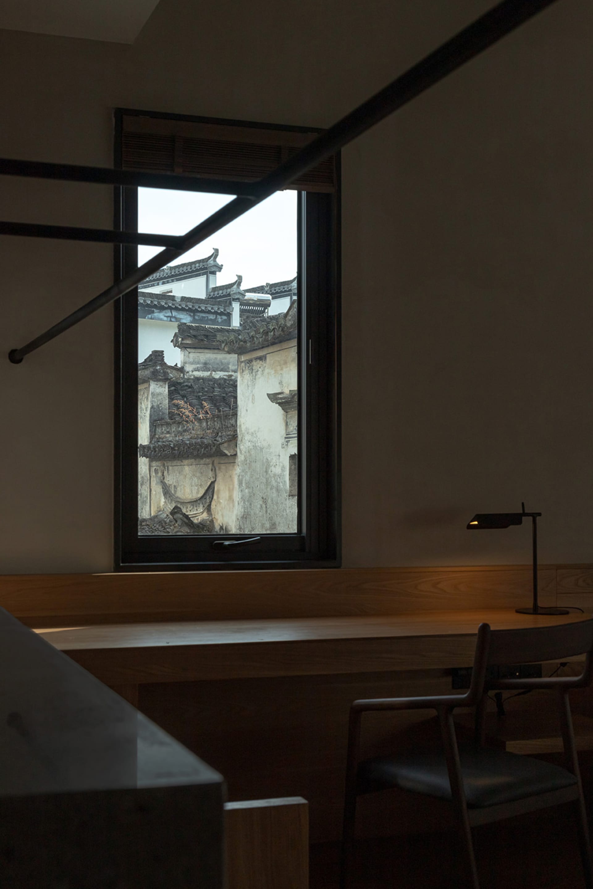 Minimalist interior space featuring a wooden window with a view of tiled roofs outside.