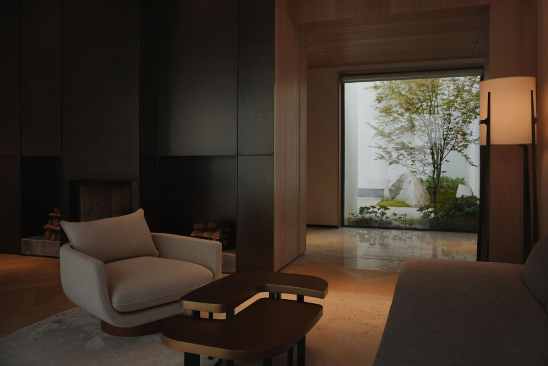 Modern living room with a beige sofa, a wooden coffee table, and a large window showing a tree and rocks outside.