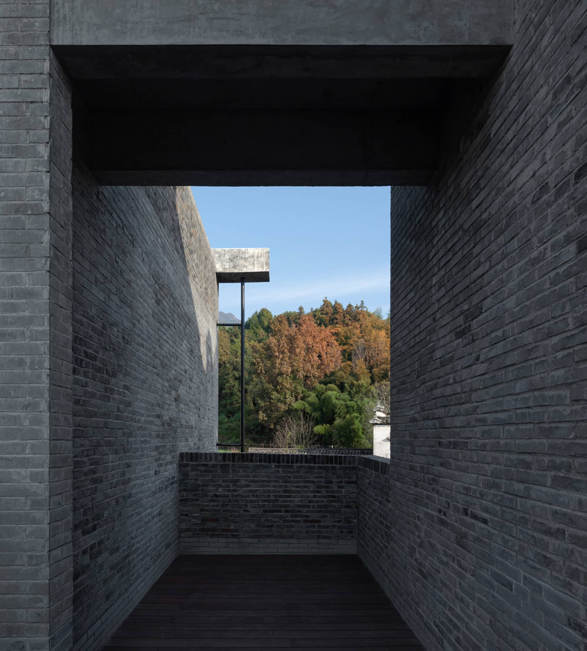 現代室內空間，磚牆映襯，敞開門口可見森林景致。