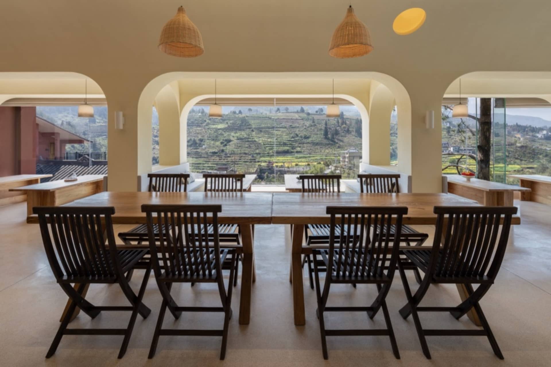A spacious cafeteria with wooden furniture and large windows providing a scenic view of the hills.