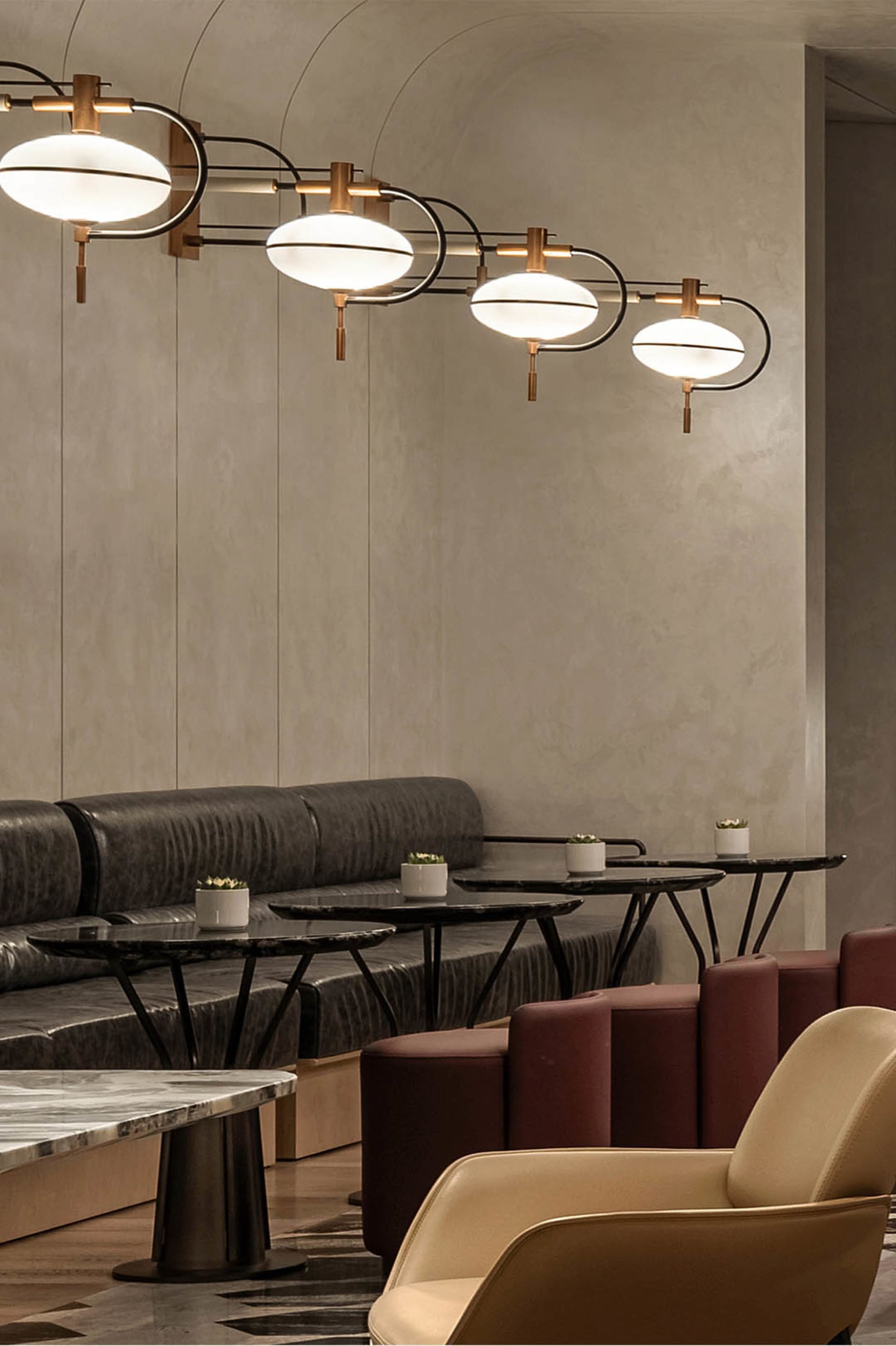Modern lounge area featuring concrete seating and tables with potted plants.