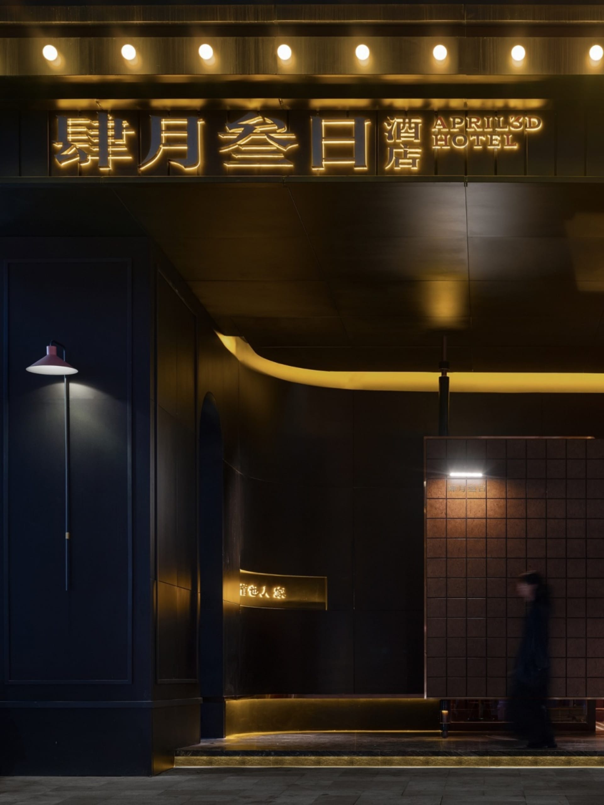 A modern hotel entryway featuring metallic lighting and concrete tiles.