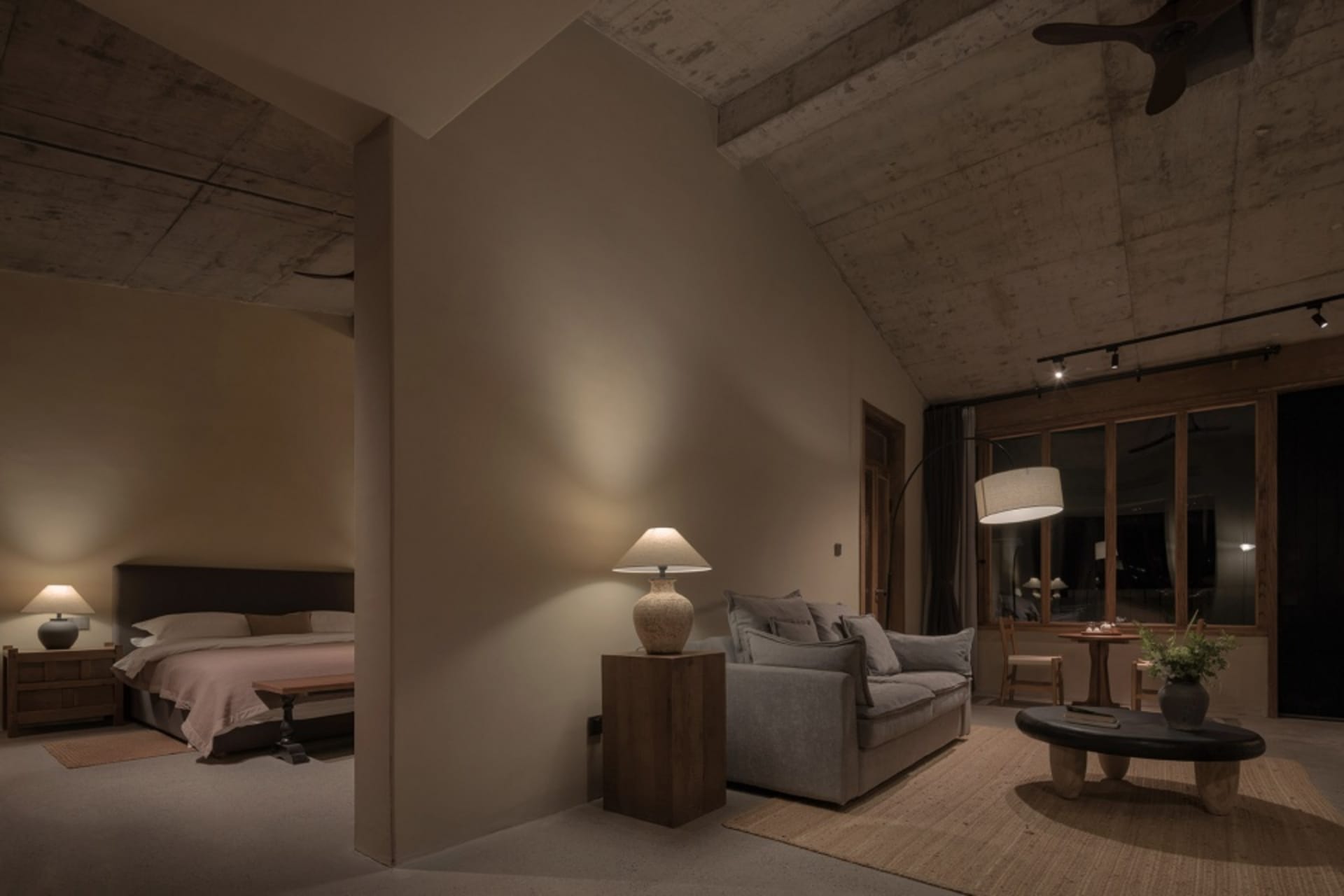Modern industrial residential interior with concrete walls and ceiling, featuring a cozy living area with a couch and floor l