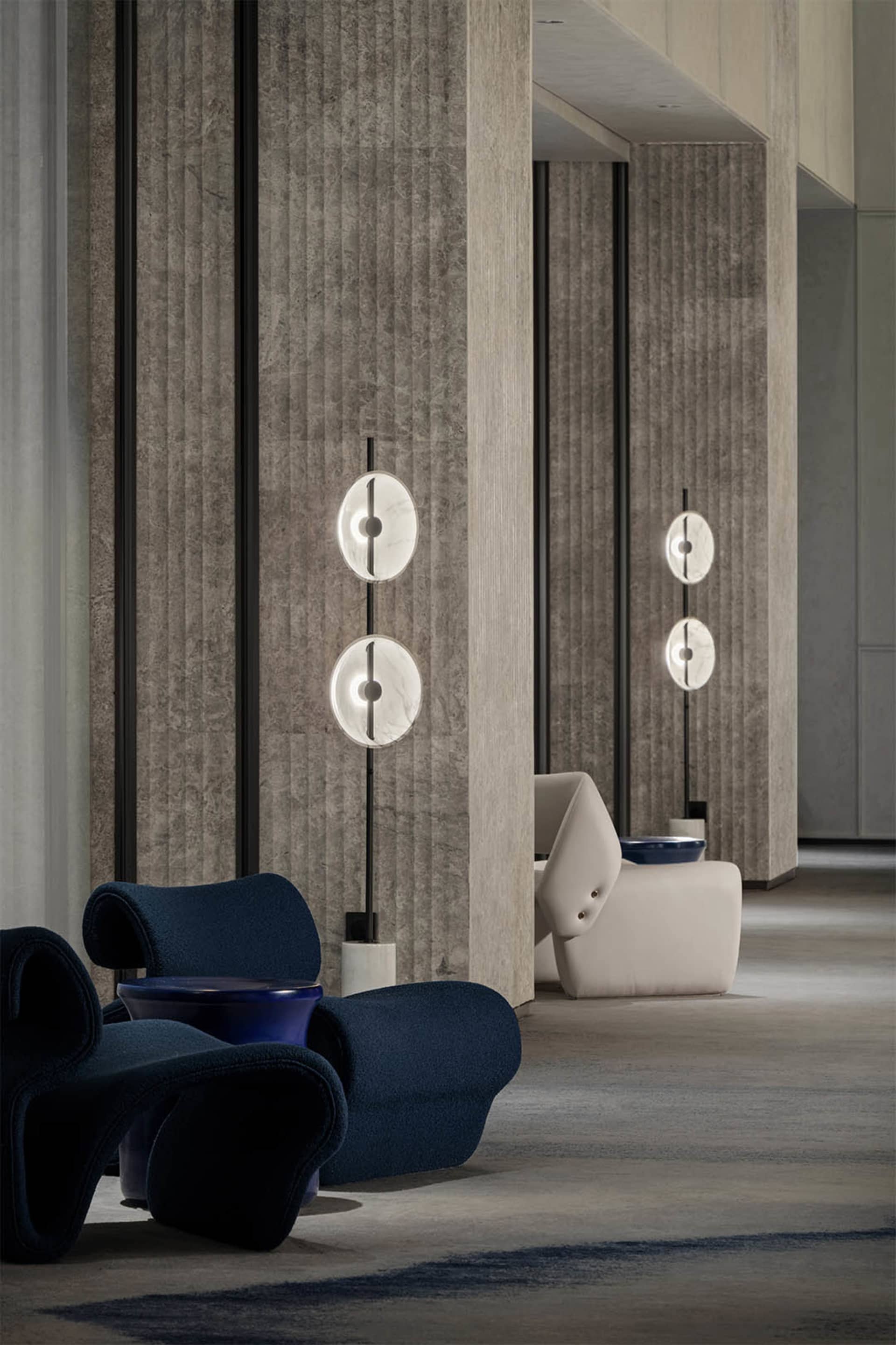 A modern minimalist lobby with sleek, concrete walls and glass lighting fixtures.