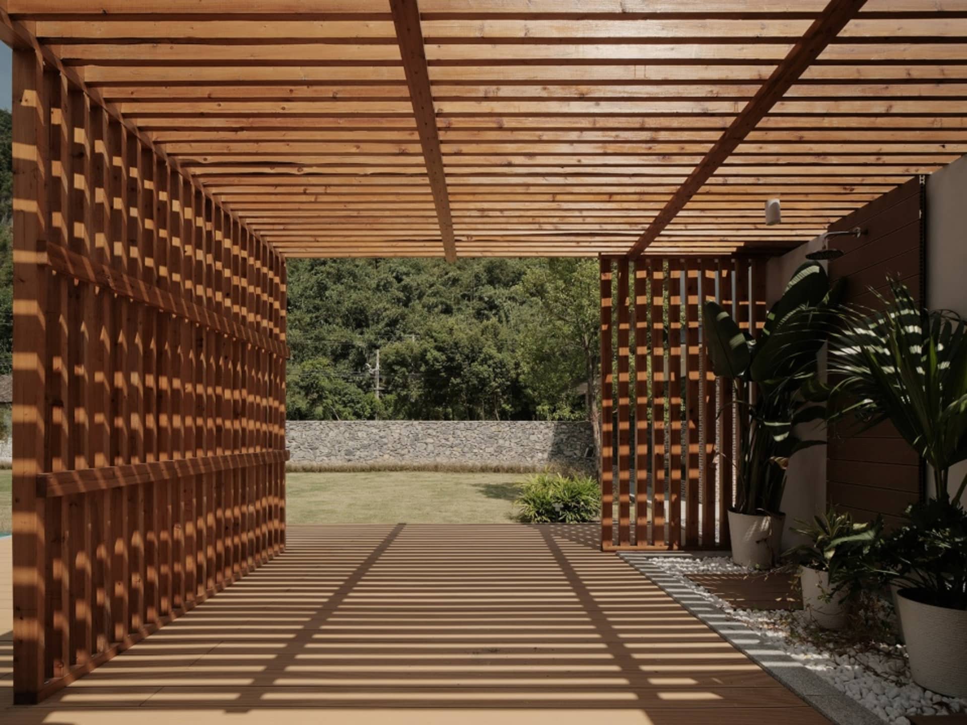 現代木質庭園露台空間,設有格柵牆、綠意植栽,以及背景的石牆。