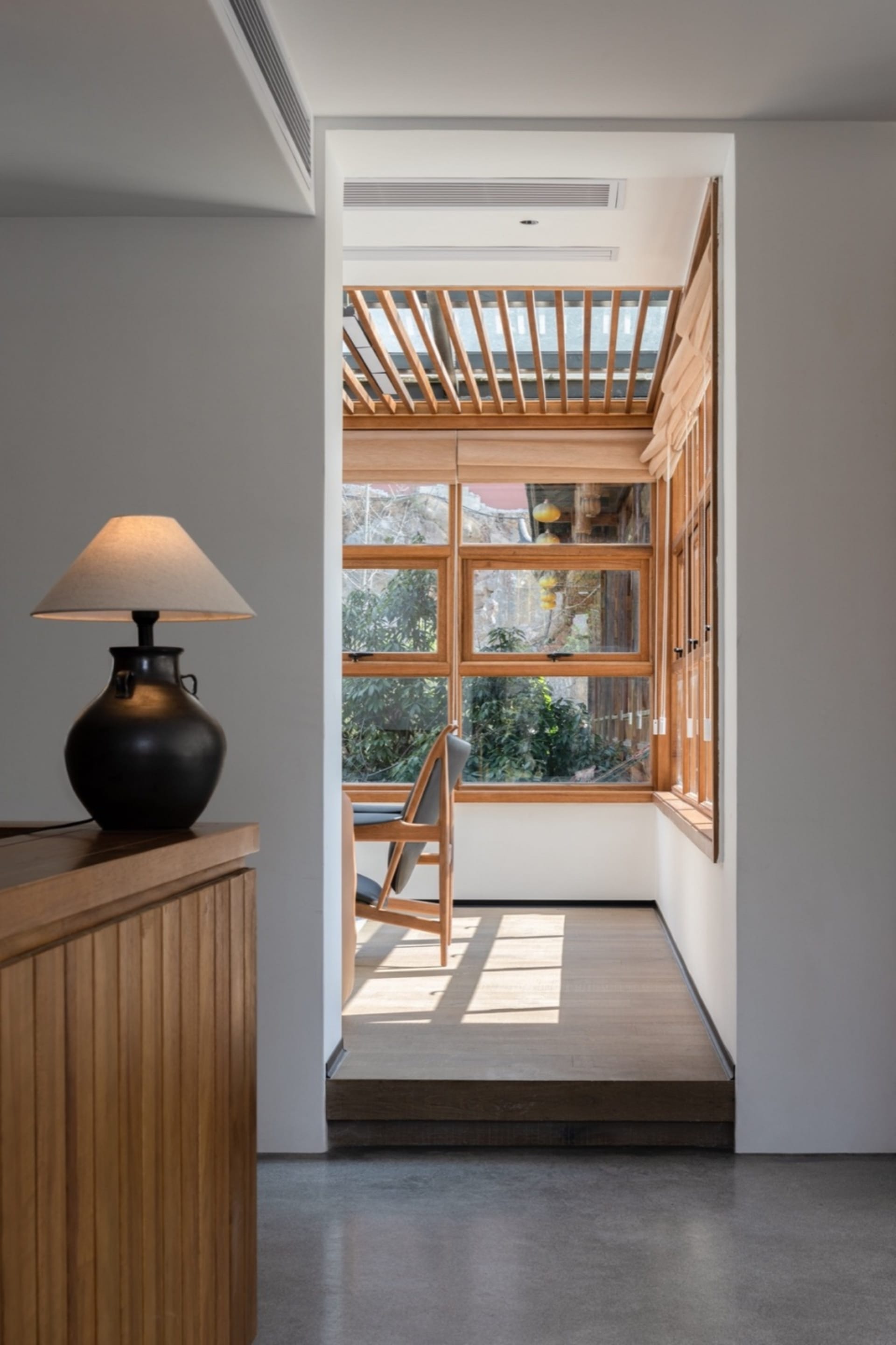 Modern interior space featuring wooden window view and minimalist design elements.