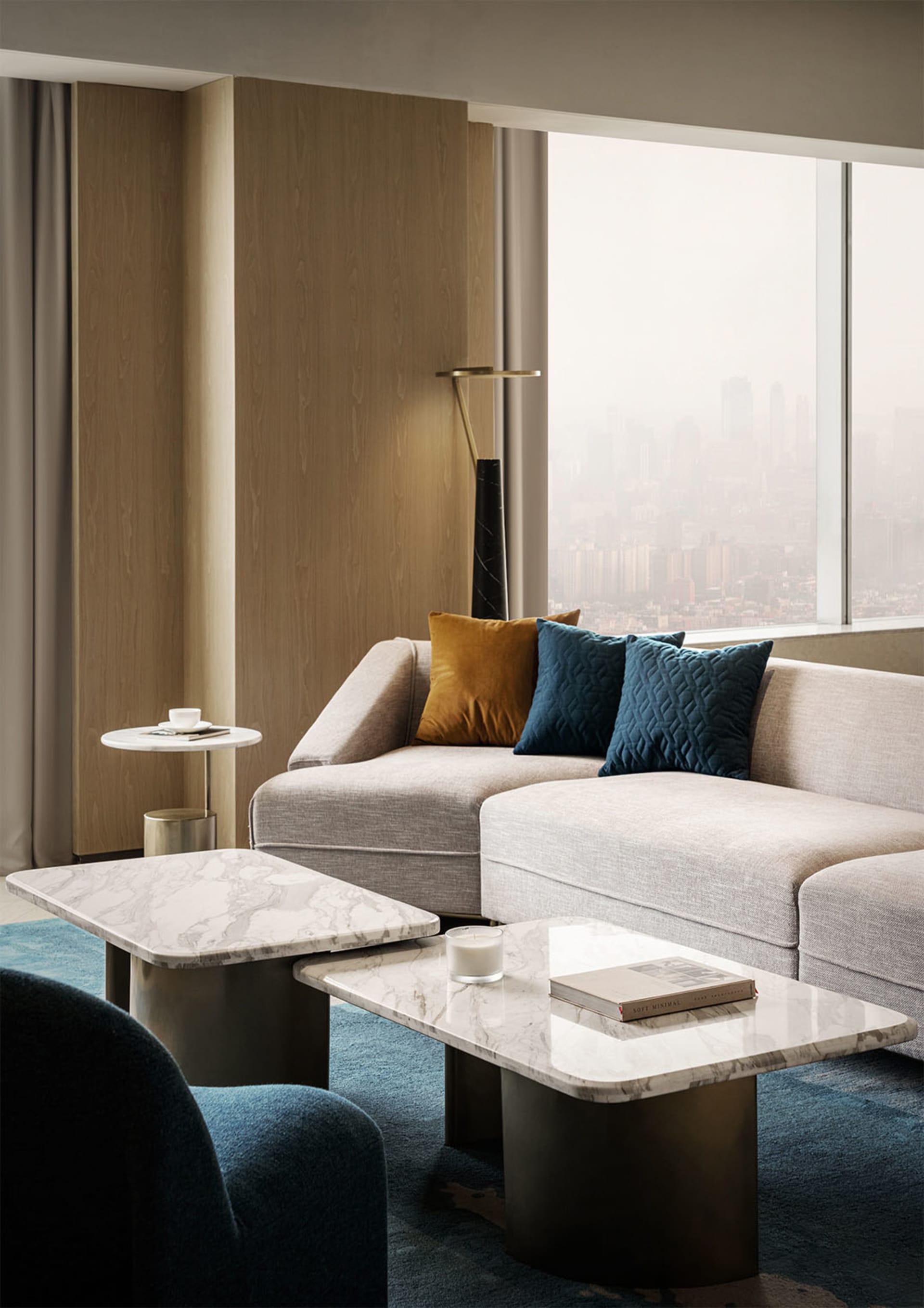 Contemporary living room featuring a couch with marble coffee tables and fabric cushions.