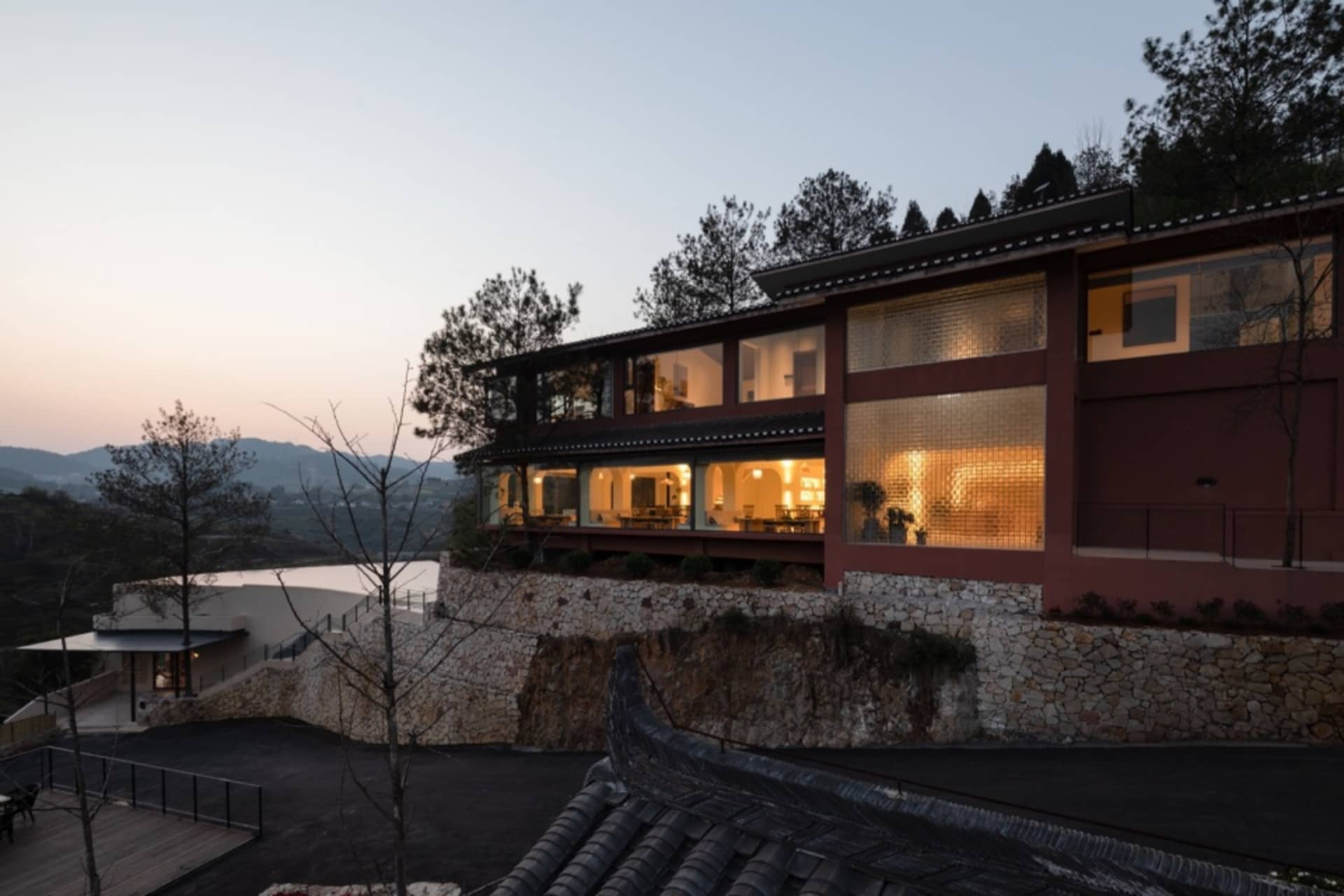 A modern residential house with concrete exterior and glass windows at dusk.
