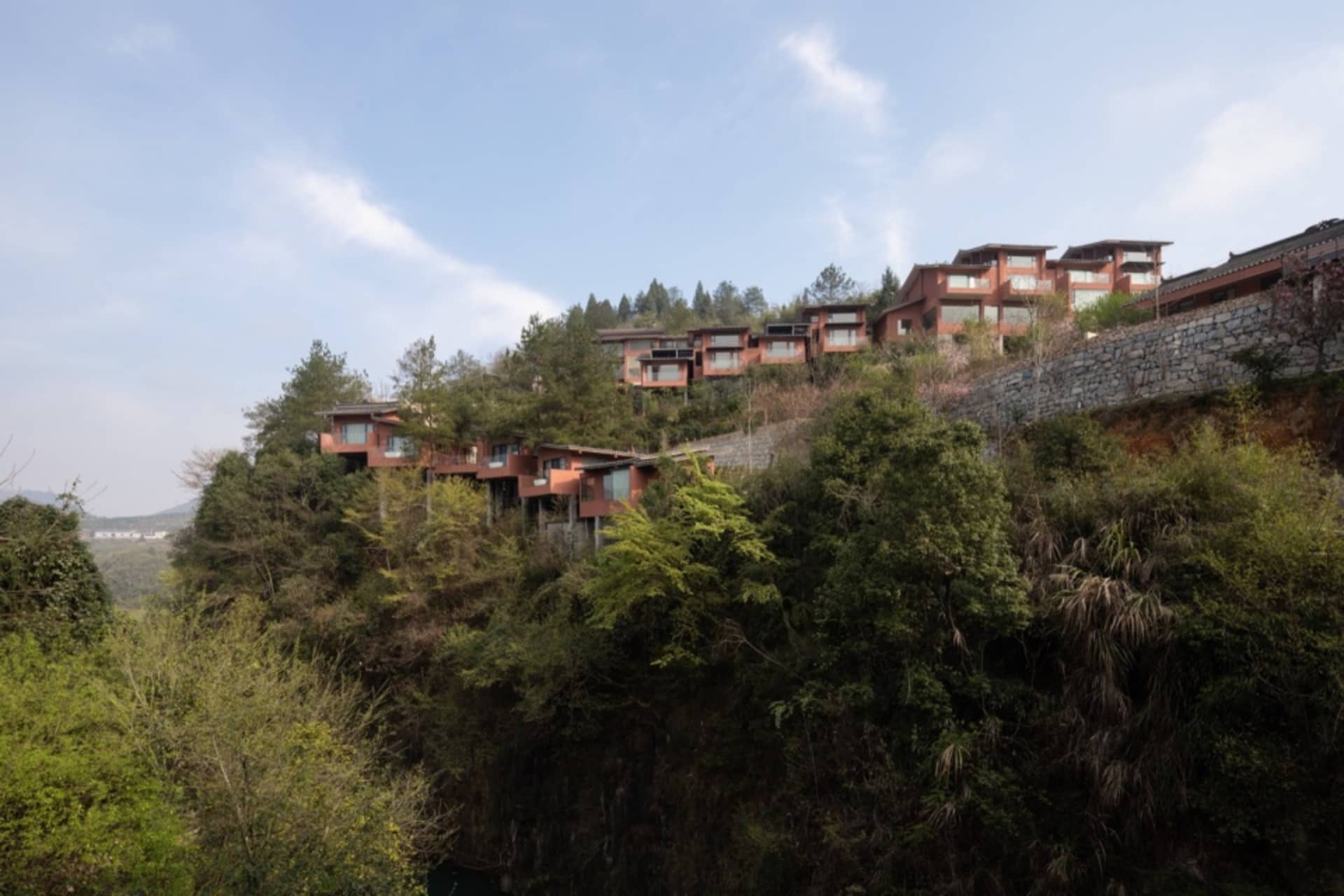 多棟住宅順著山坡而建,周圍環繞樹木與植被。