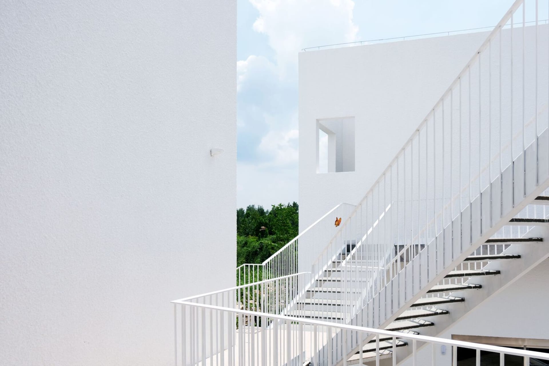 White metal staircase with railings and a view of greenery in the background.