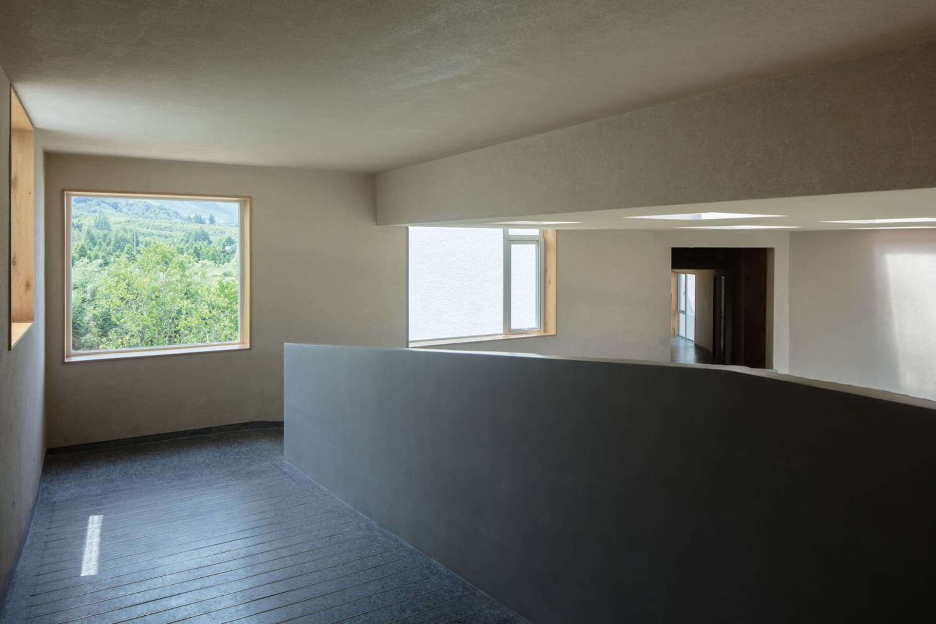 A sleek modern-industrial interior with concrete walls and a view of the sky through a large window.