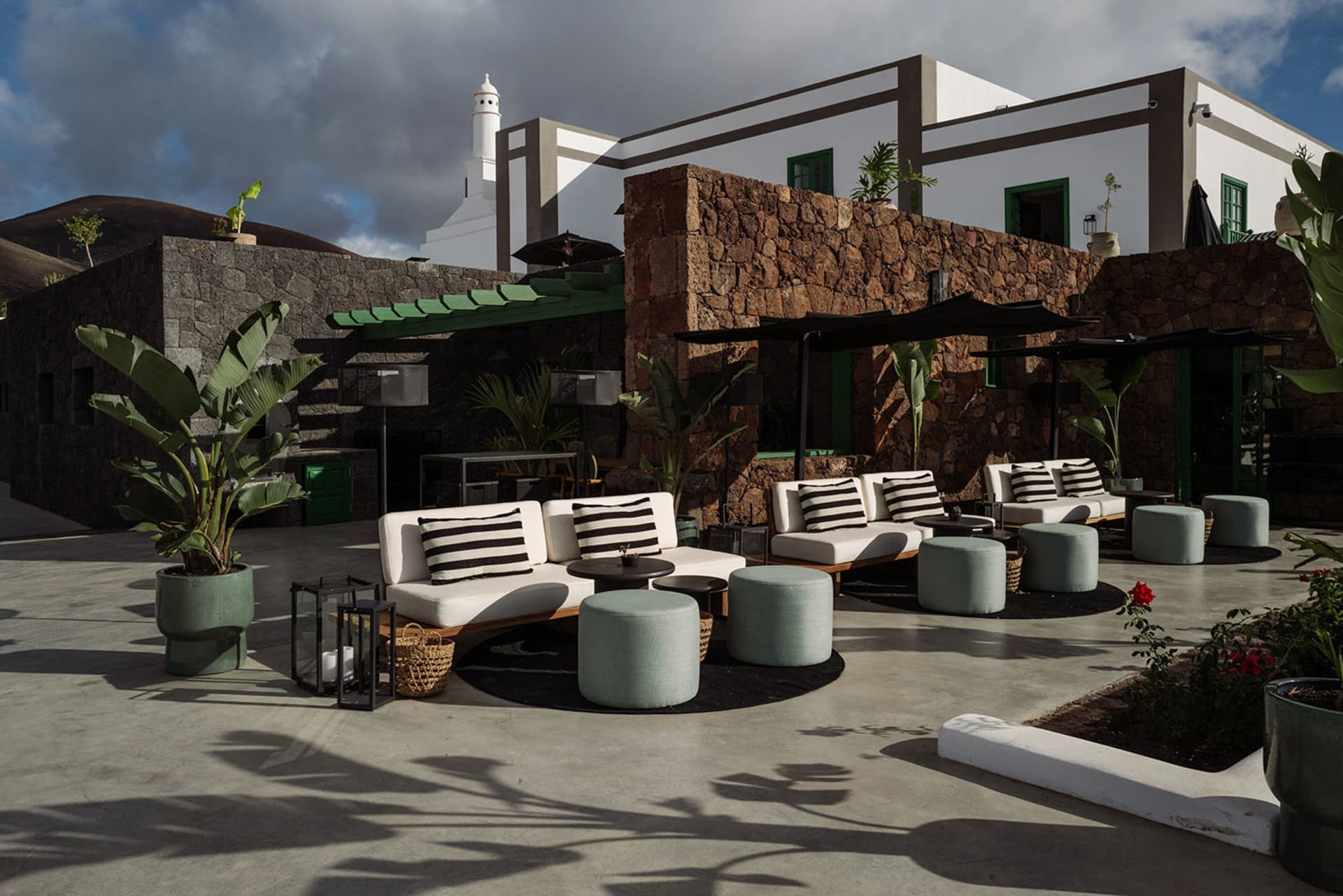 Outdoor seating area of a hotel patio with concrete floors, white sofas, and greenery.