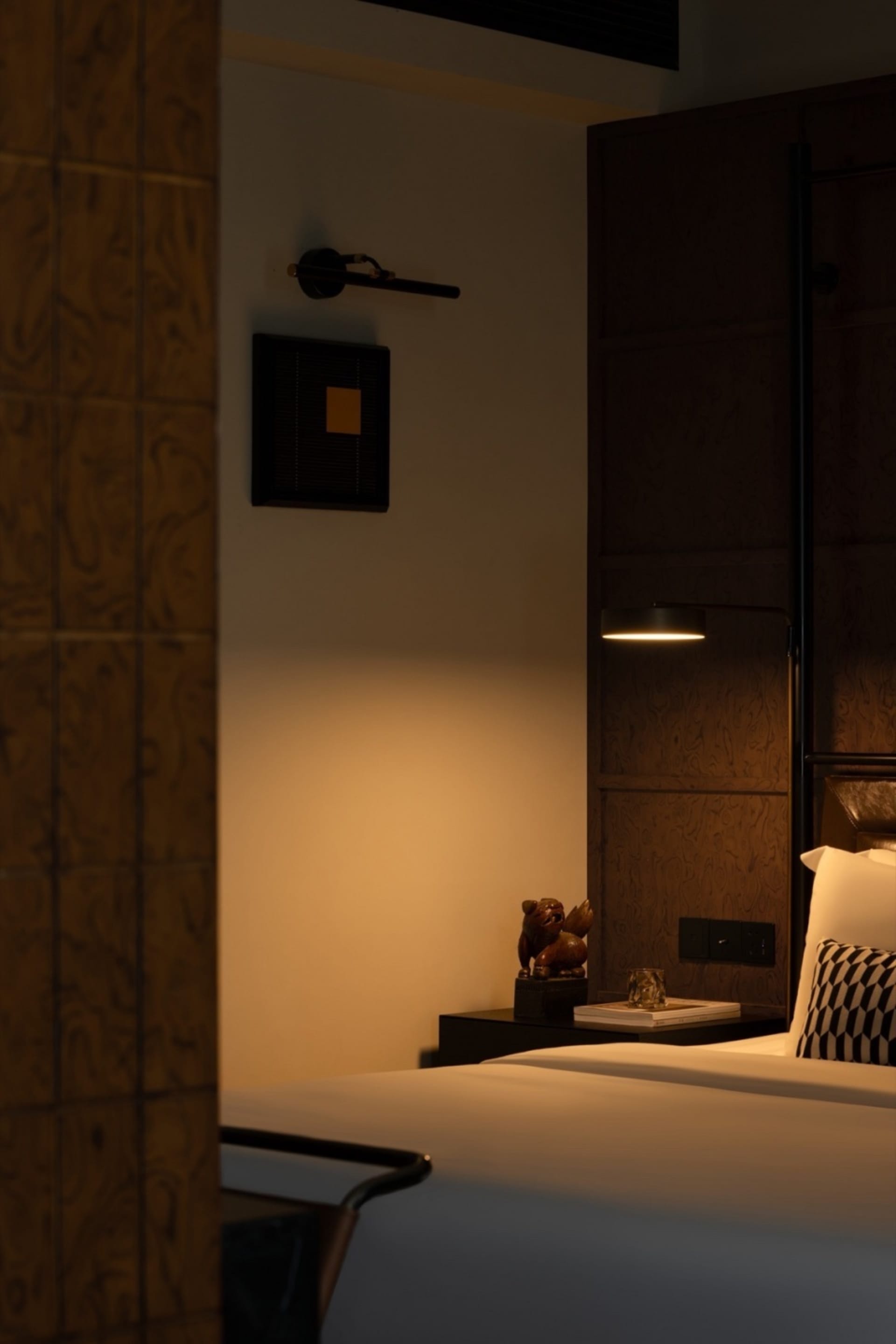 Minimalist bedroom with wooden details, lit by warm ambient lighting.