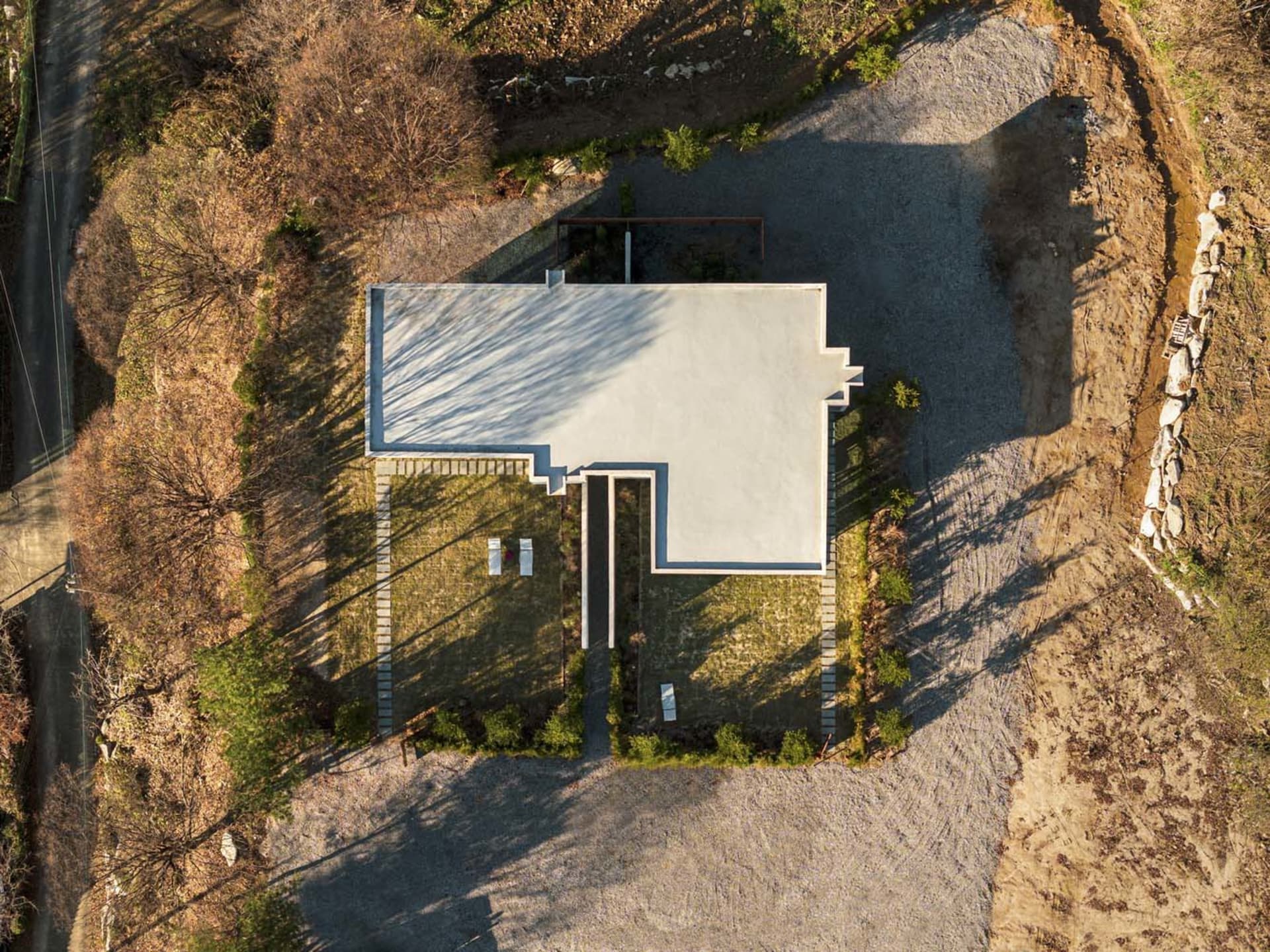 A modern house with a minimalist architectural design, featuring concrete surfaces and a flat roof.