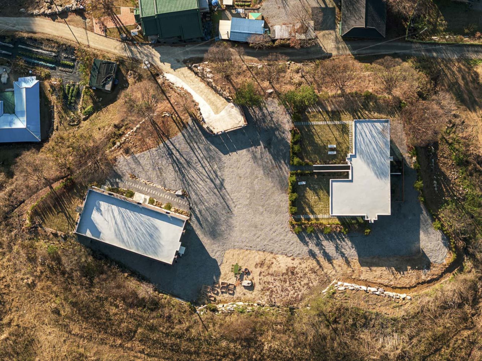 A modern residential exterior with a concrete structure and gravel driveway.
