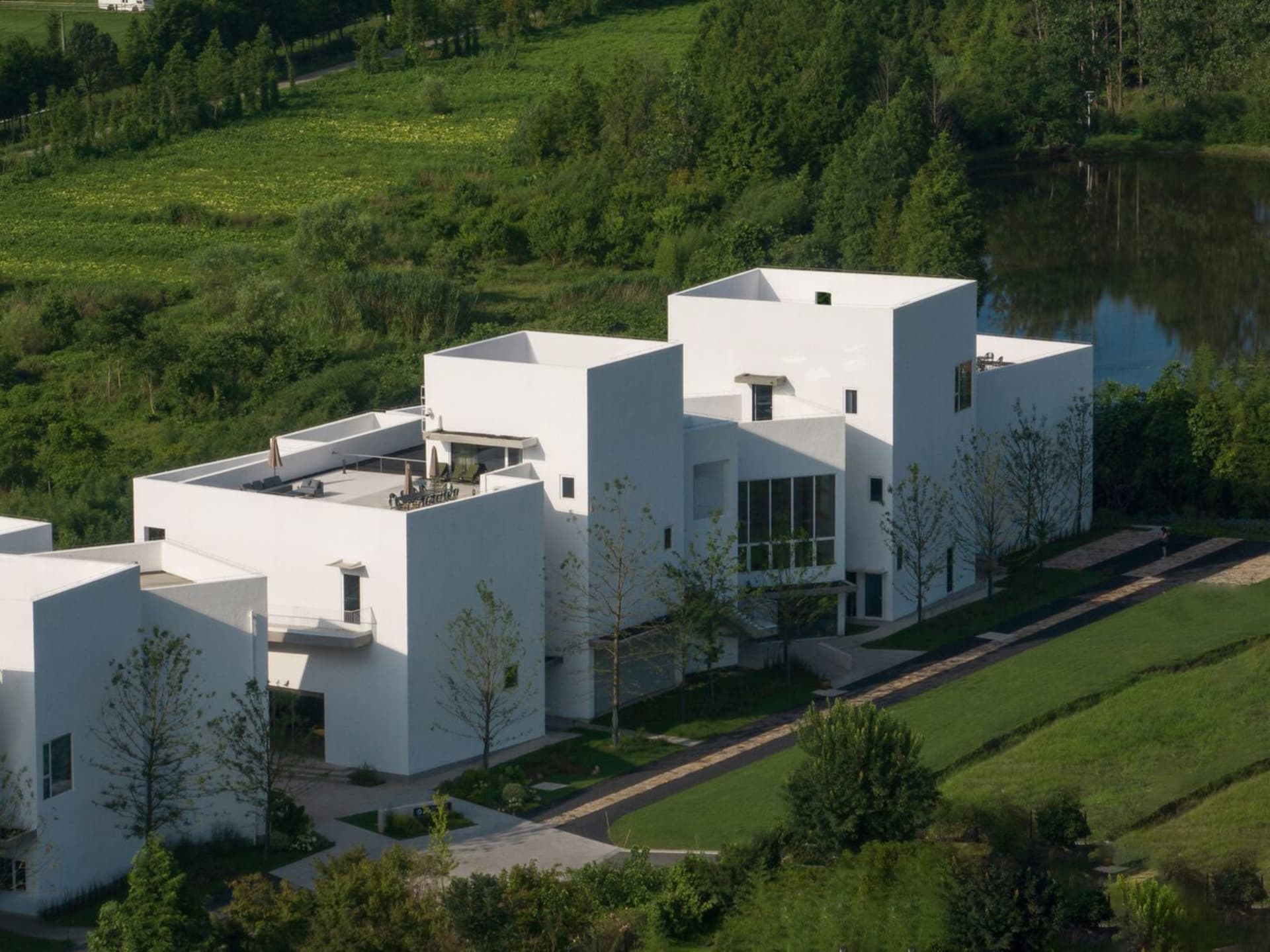 Modern residential building with white concrete exterior and large glass windows.