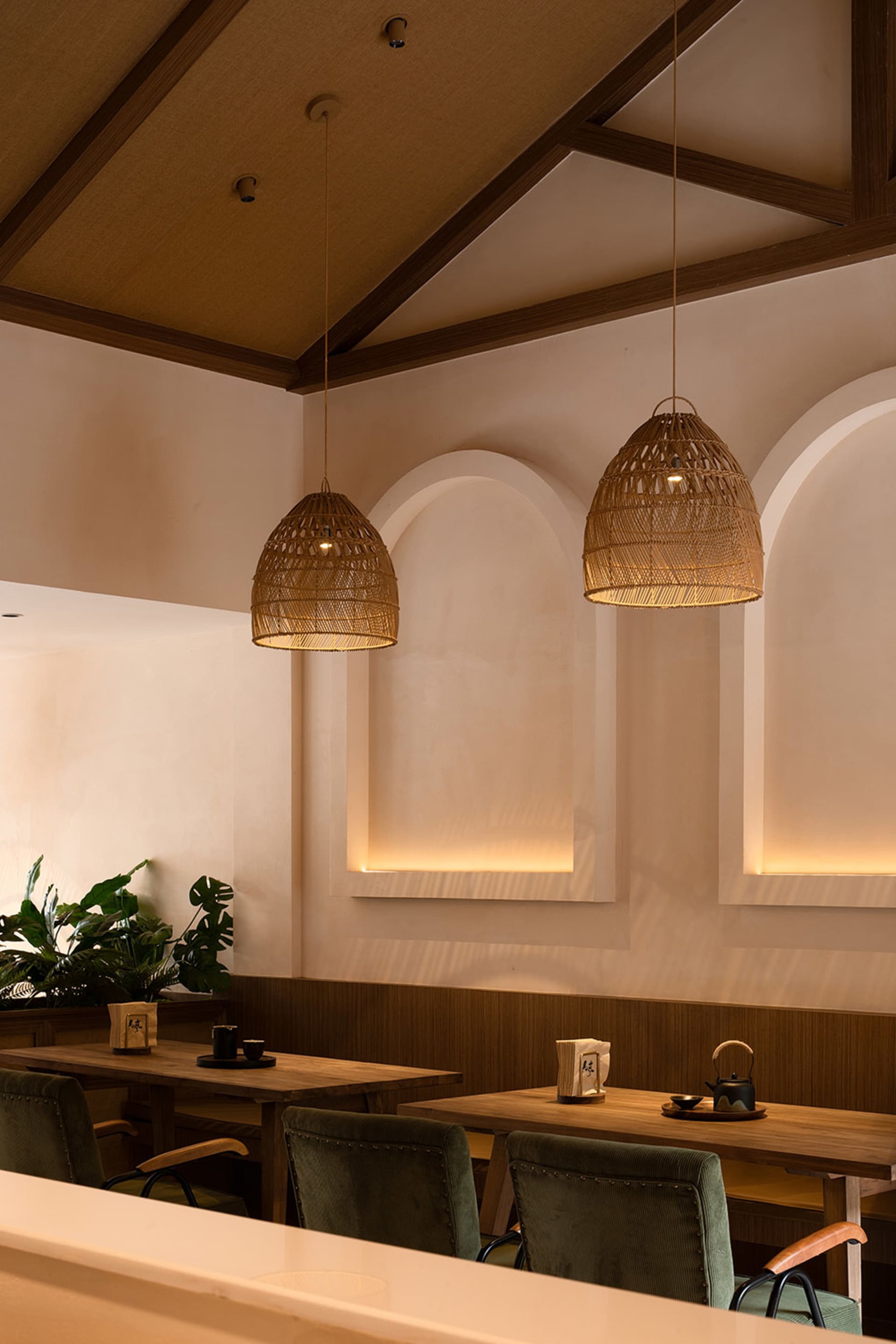 A photograph of a modern restaurant interior featuring wooden furniture and woven basket lamp shades.
