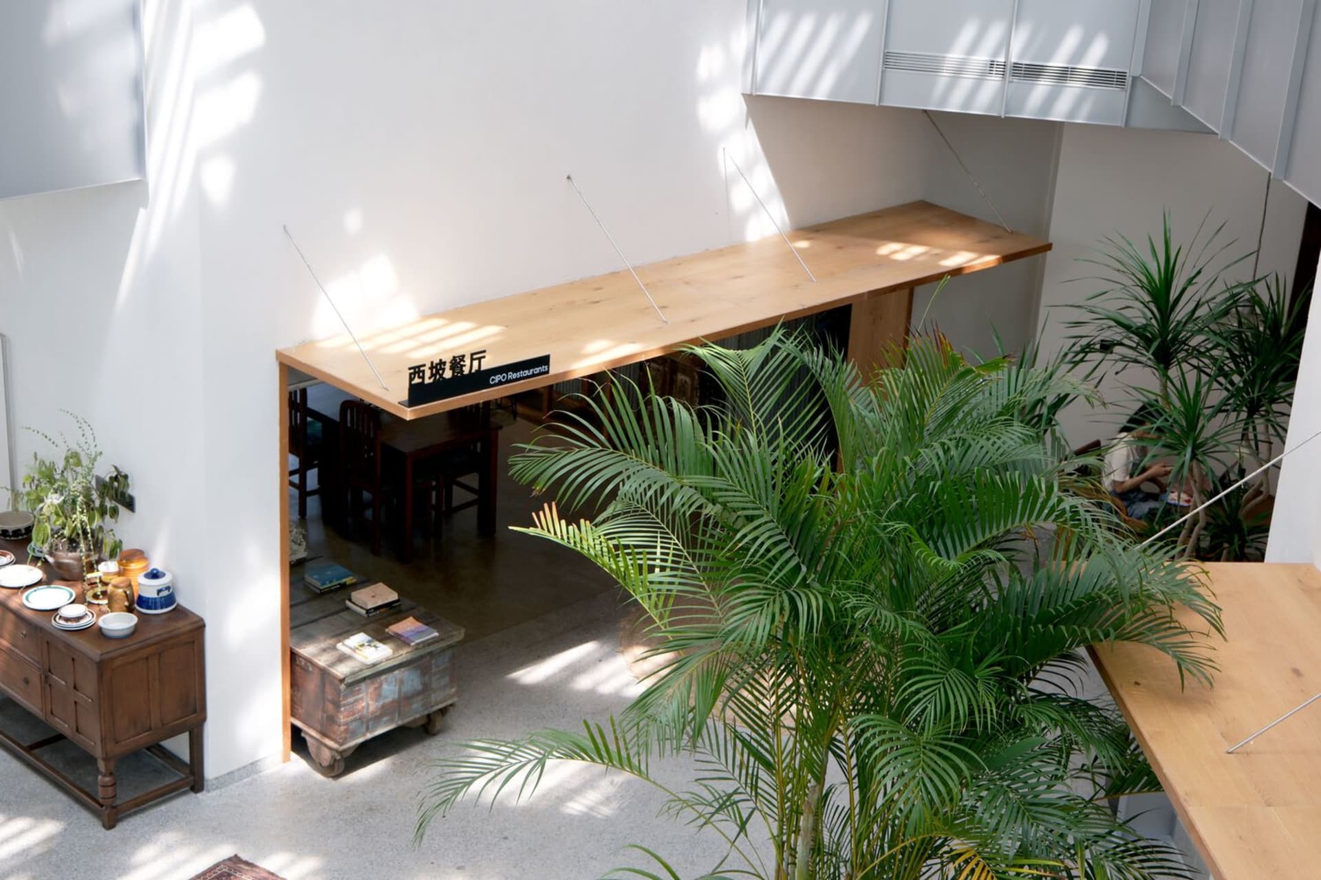 A modern restaurant interior with wooden tables and green plants.