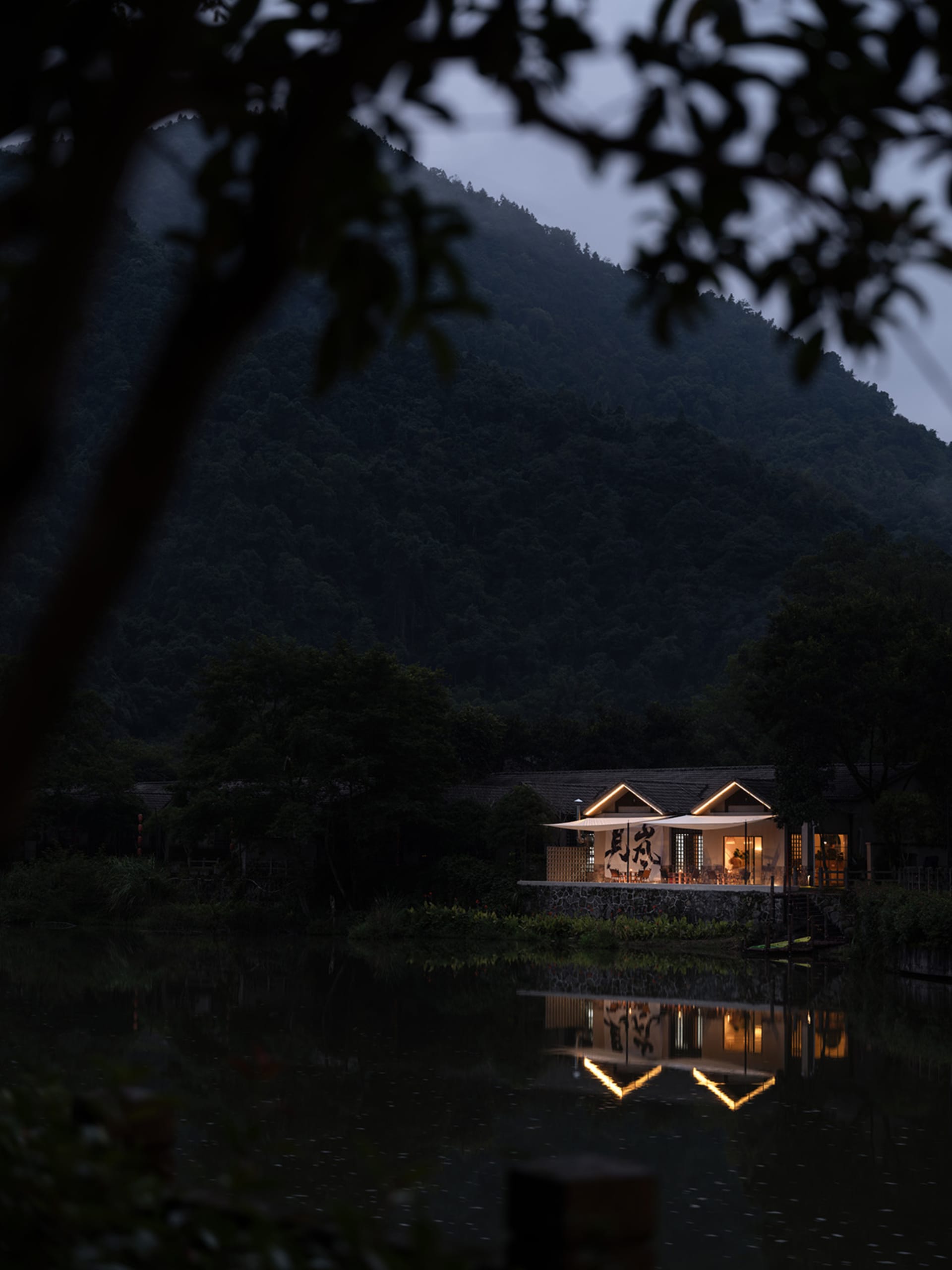 黃昏時分，木質材料的鄉村住宅建築倒映在寧靜的湖面上。