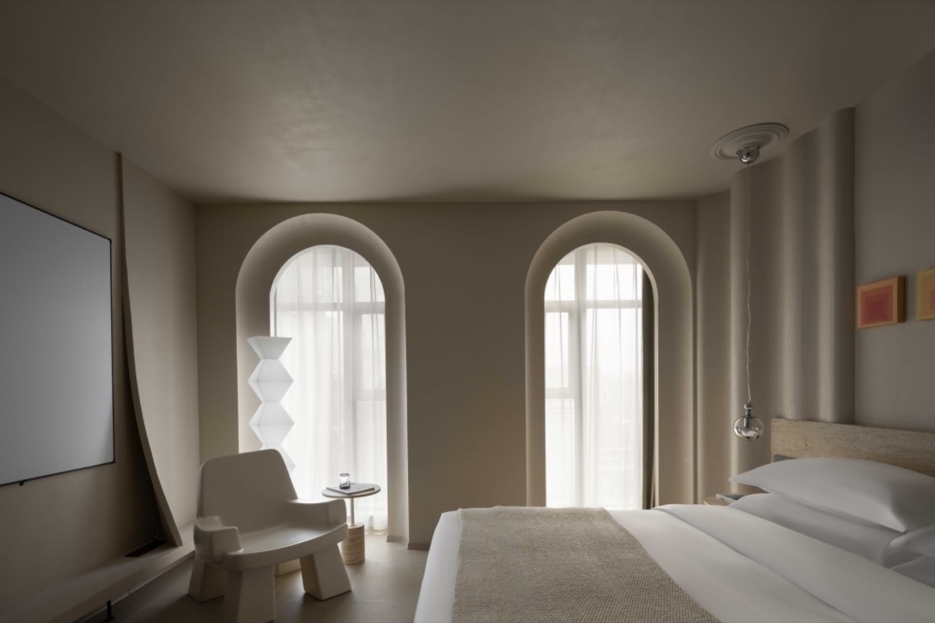 A minimalist bedroom with beige and white furniture and a neutral color palette.
