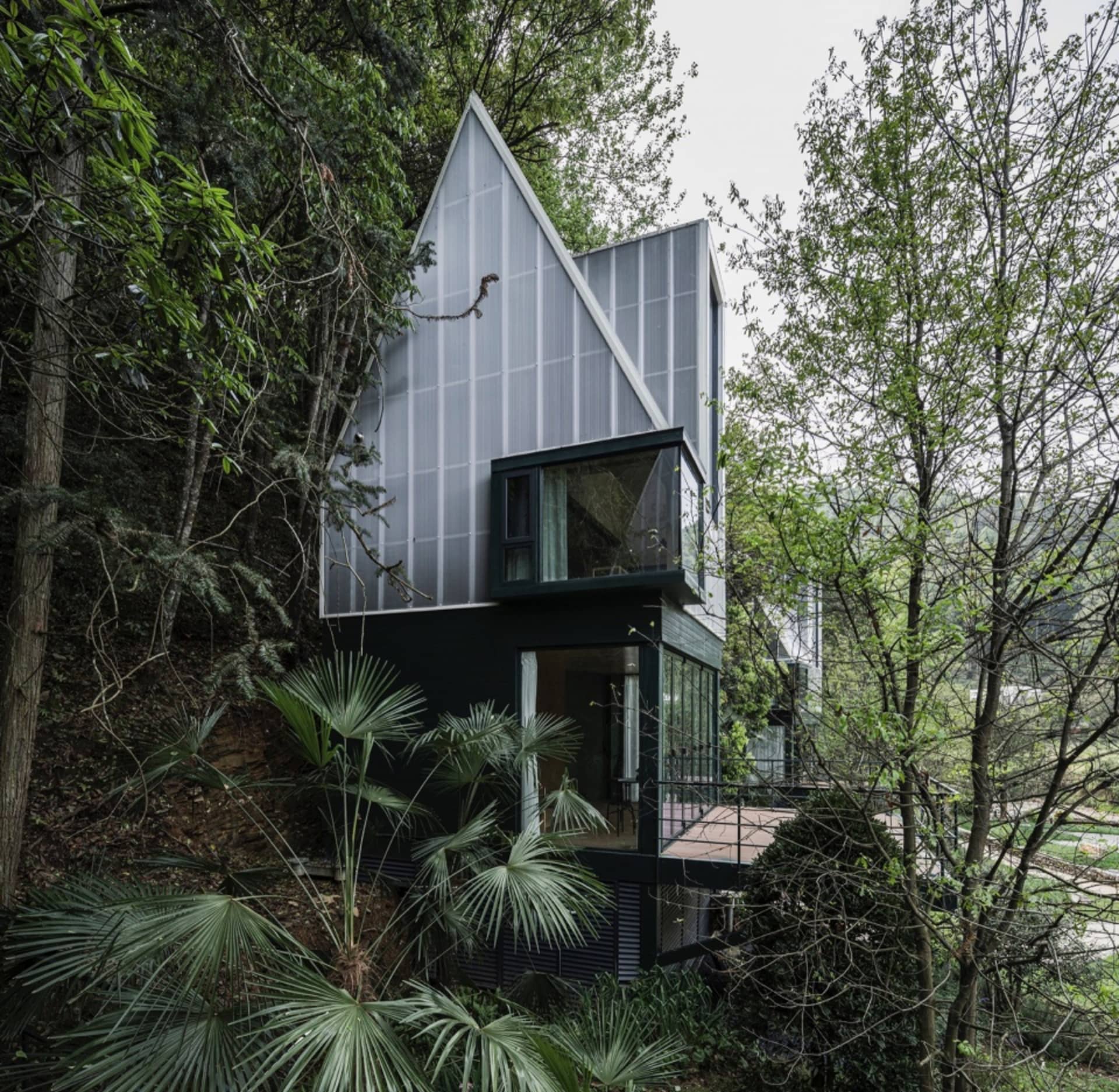 Modern residential house with metal exterior surrounded by trees and greenery.