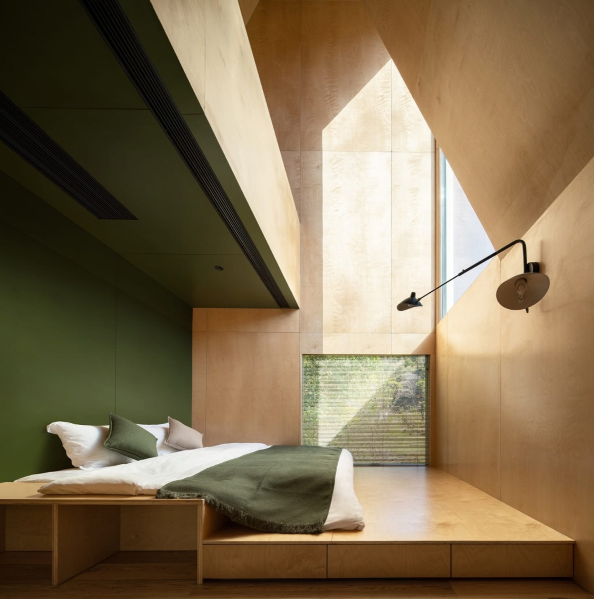 A modern bedroom featuring a wooden platform bed with green bedding and blinds, designed with minimalist aesthetics.