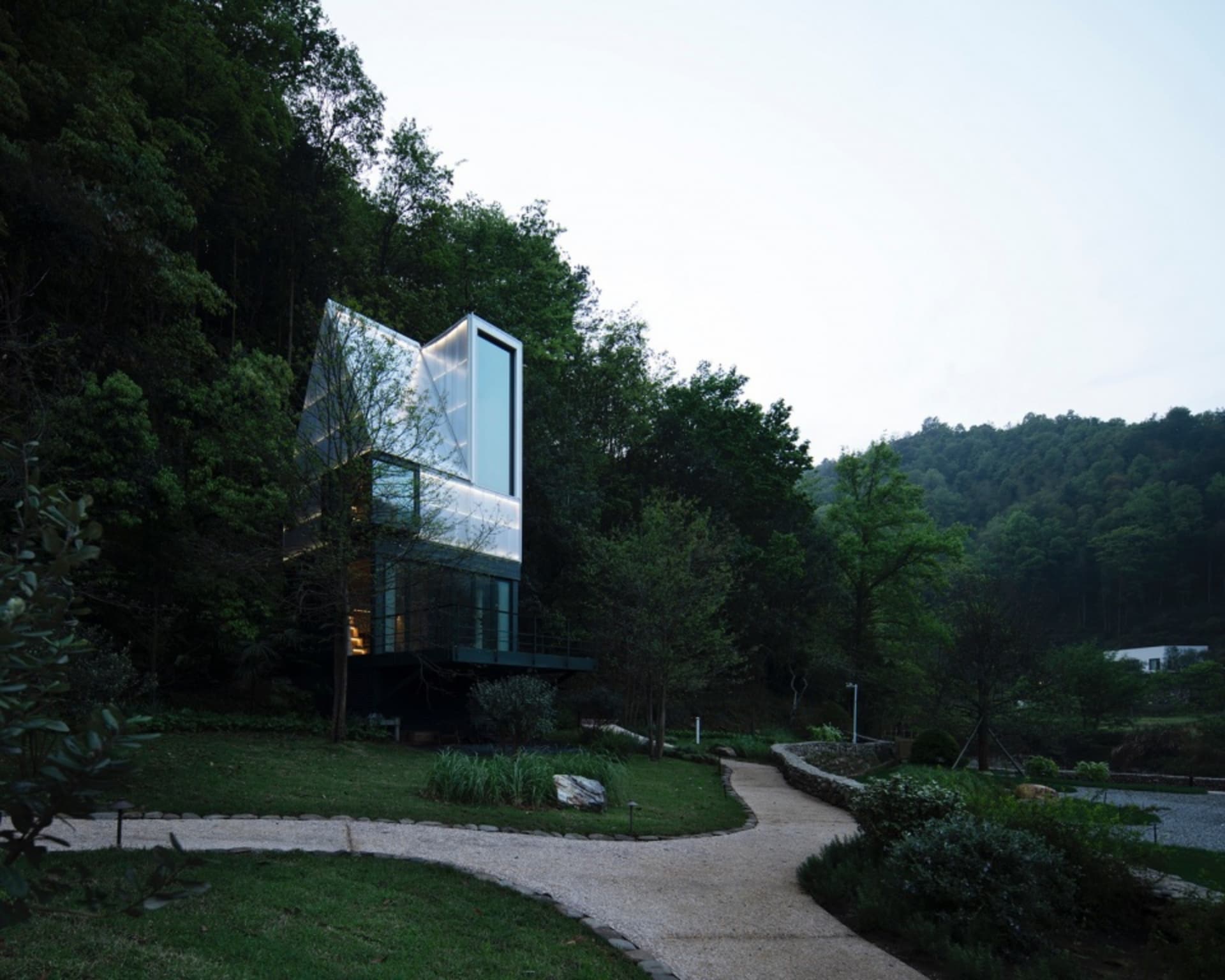A modern house with glass cabinets and a gravel path.