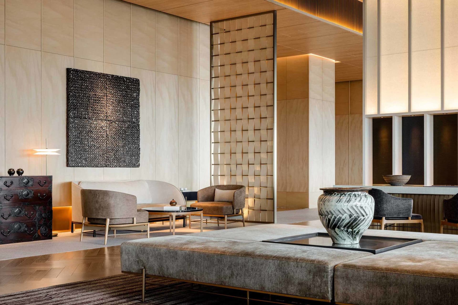 A modern living room featuring beige upholstered furniture, wooden paneling, and metallic accents.