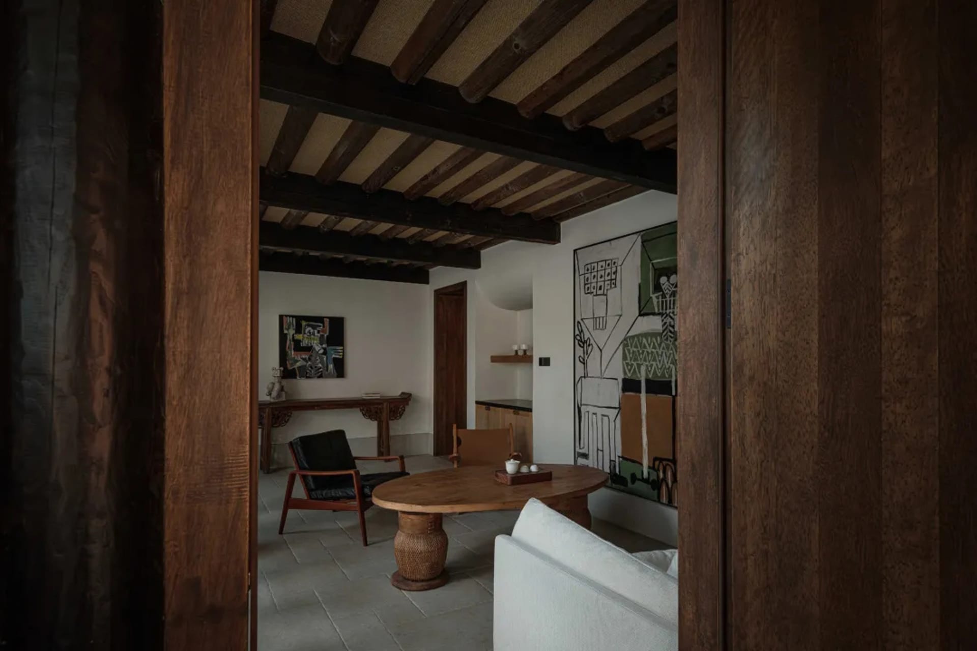 A modern living room with wooden furniture, leather accents, and concrete flooring.