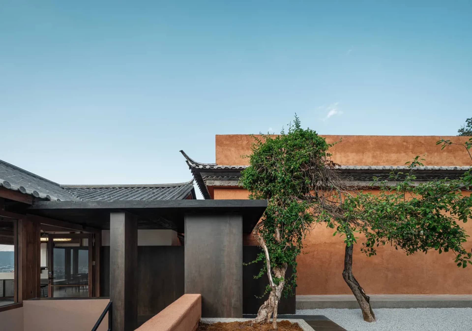一棟擁有陶土外牆的現代建築， foreground 有一棵樹。