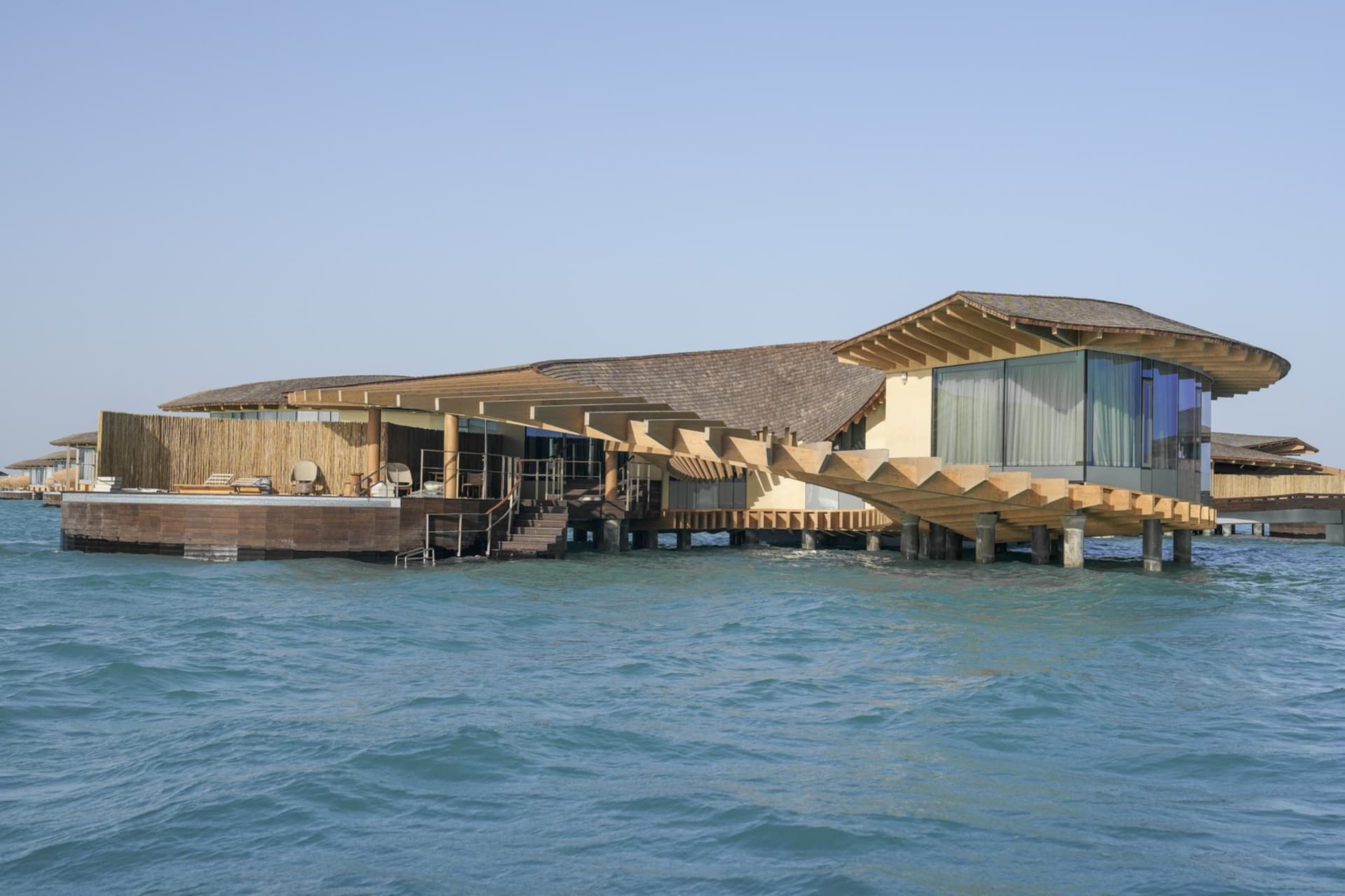Modern, minimalist waterfront resort buildings floating on the ocean.