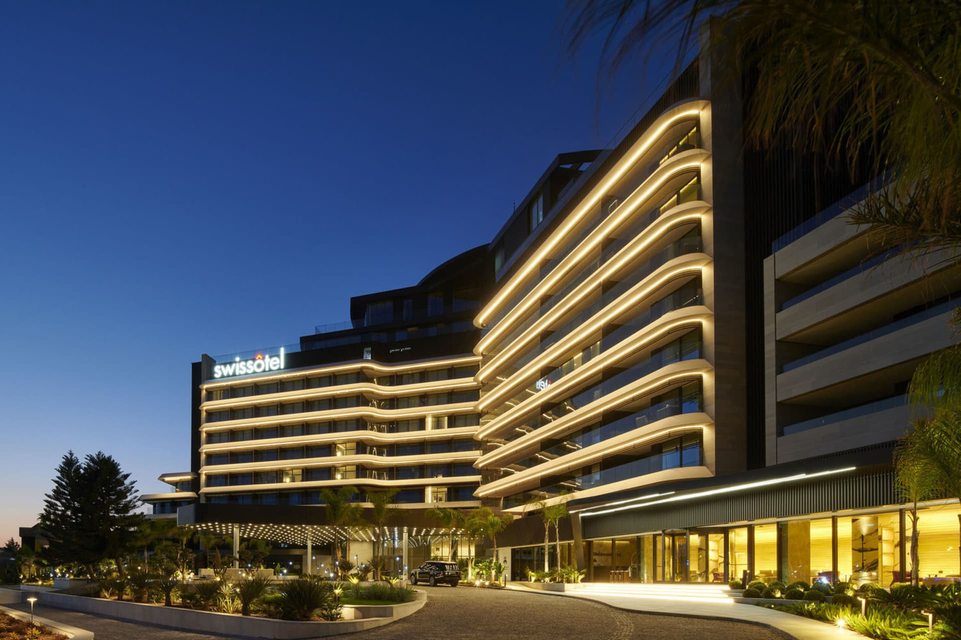 Swissotel 飯店建築夜間燈光照亮,呈現現代建築設計。
