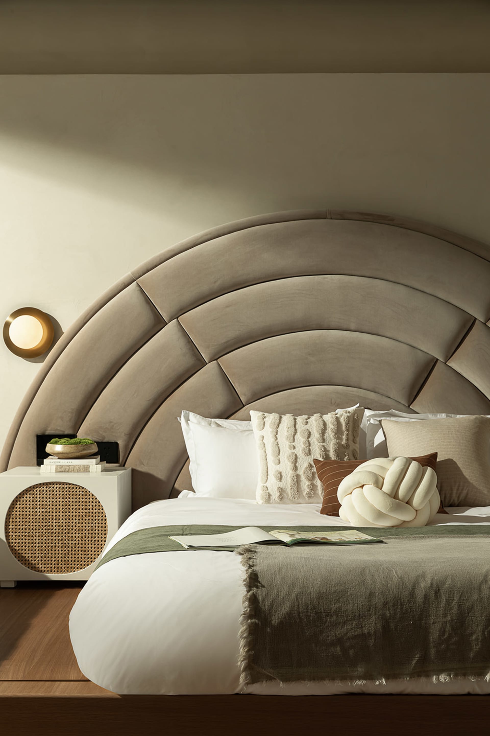 Modern minimalist bedroom with a textured beige headboard and wooden flooring.