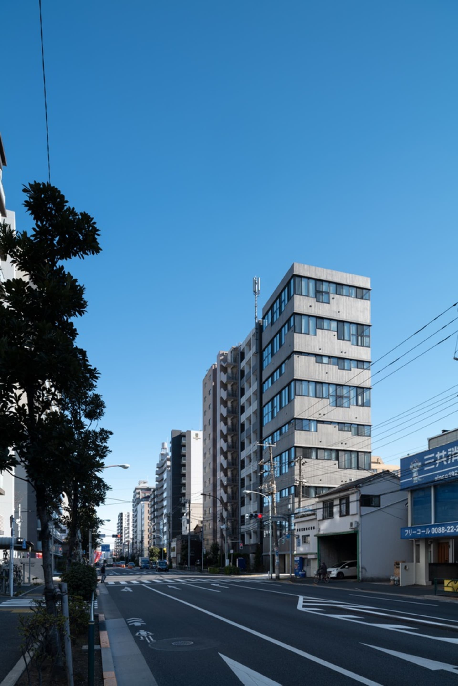 A clear blue sky with modern concrete buildings and a pedestrian sidewalk.
