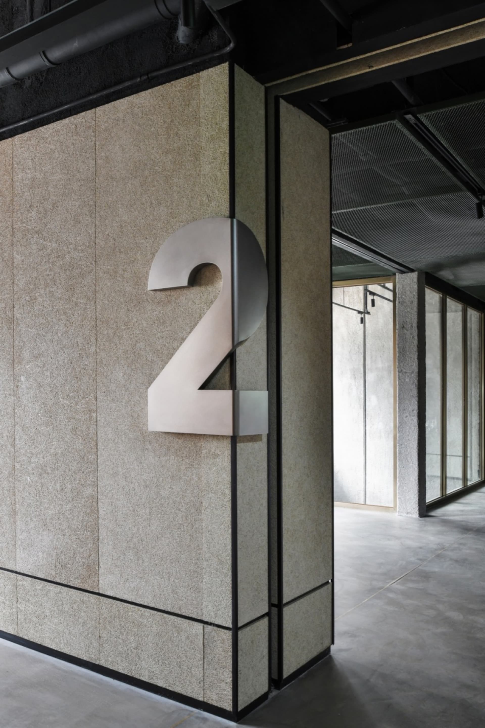A modern building number sign made of metal attached to a wall.