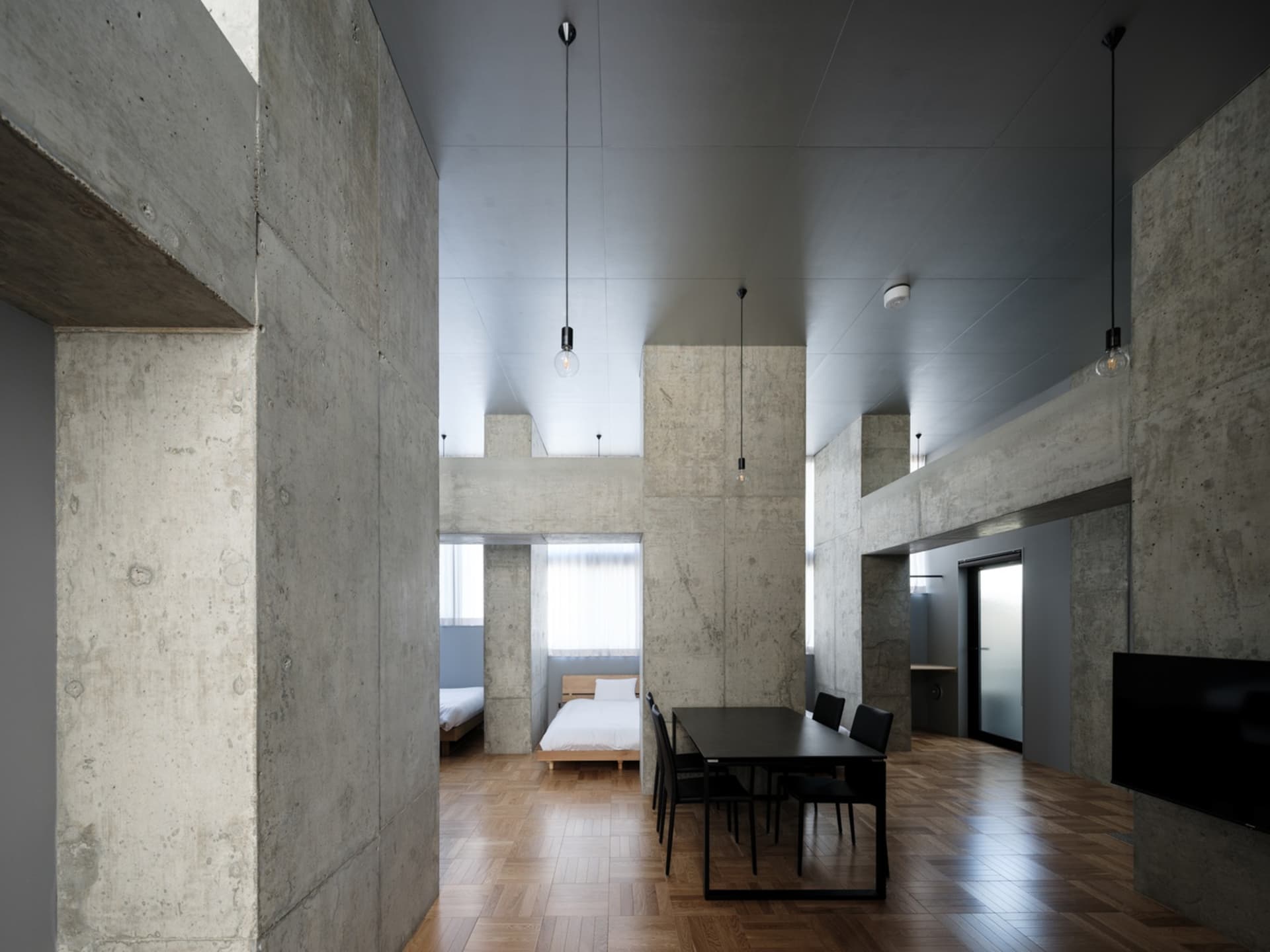A photograph showcasing a modern industrial residential interior with concrete walls and wooden parquet flooring.