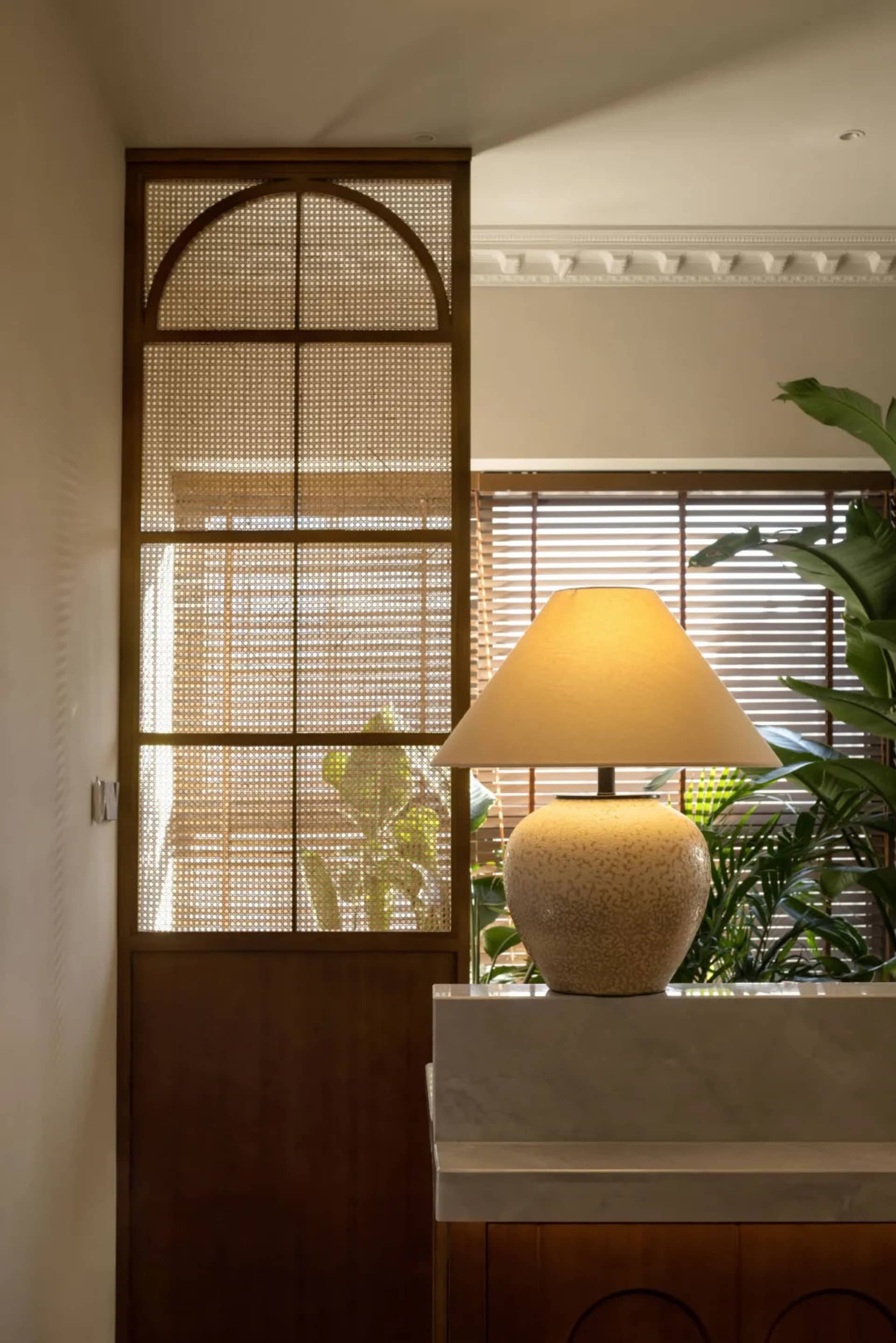 A ceramic lamp with a conical shade illuminates a space, adding a warm glow.