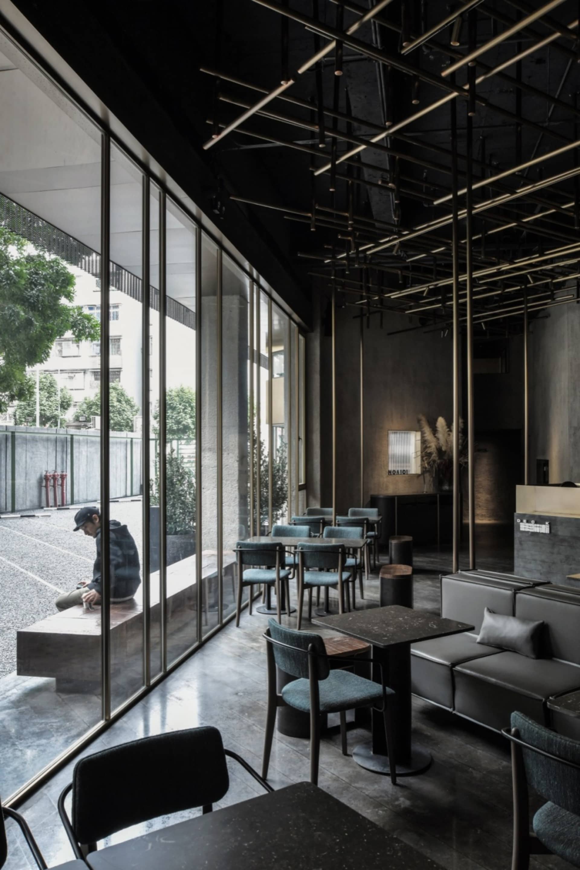 A modern industrial restaurant interior with metal and concrete elements and large windows.